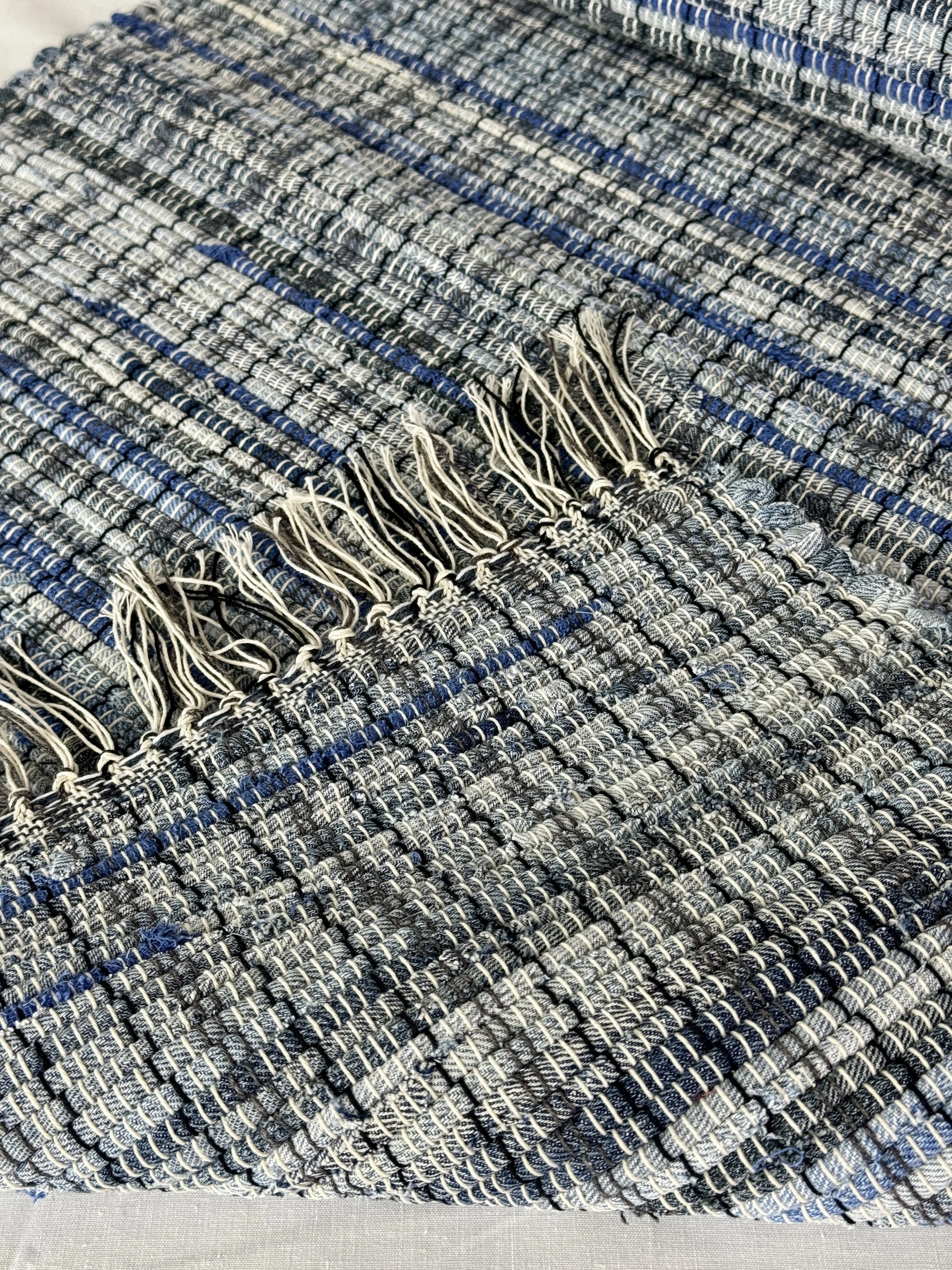 Folded handwoven rag rug showing reverse side and fringe