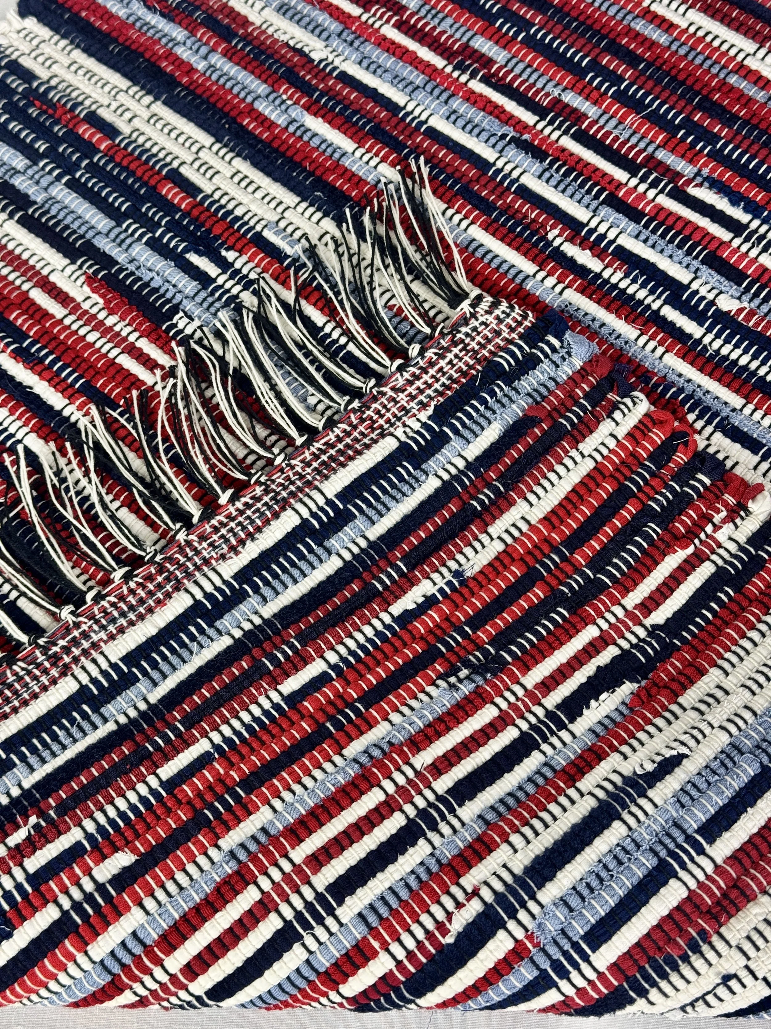 Close up handmade rag rug featuring texture and fringe ends