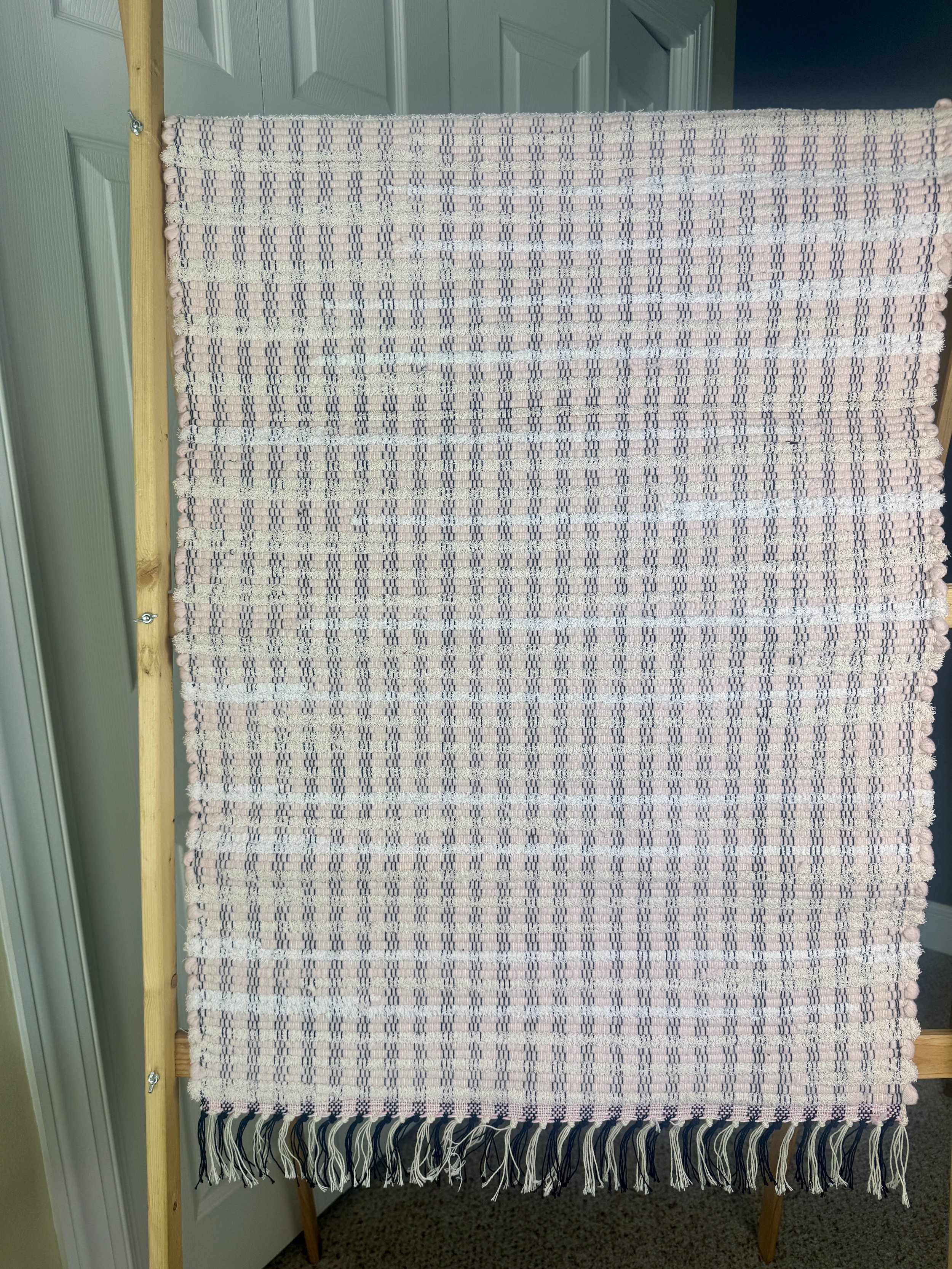 Hanging handmade recycled cotton  rag rug showing pattern and fringe