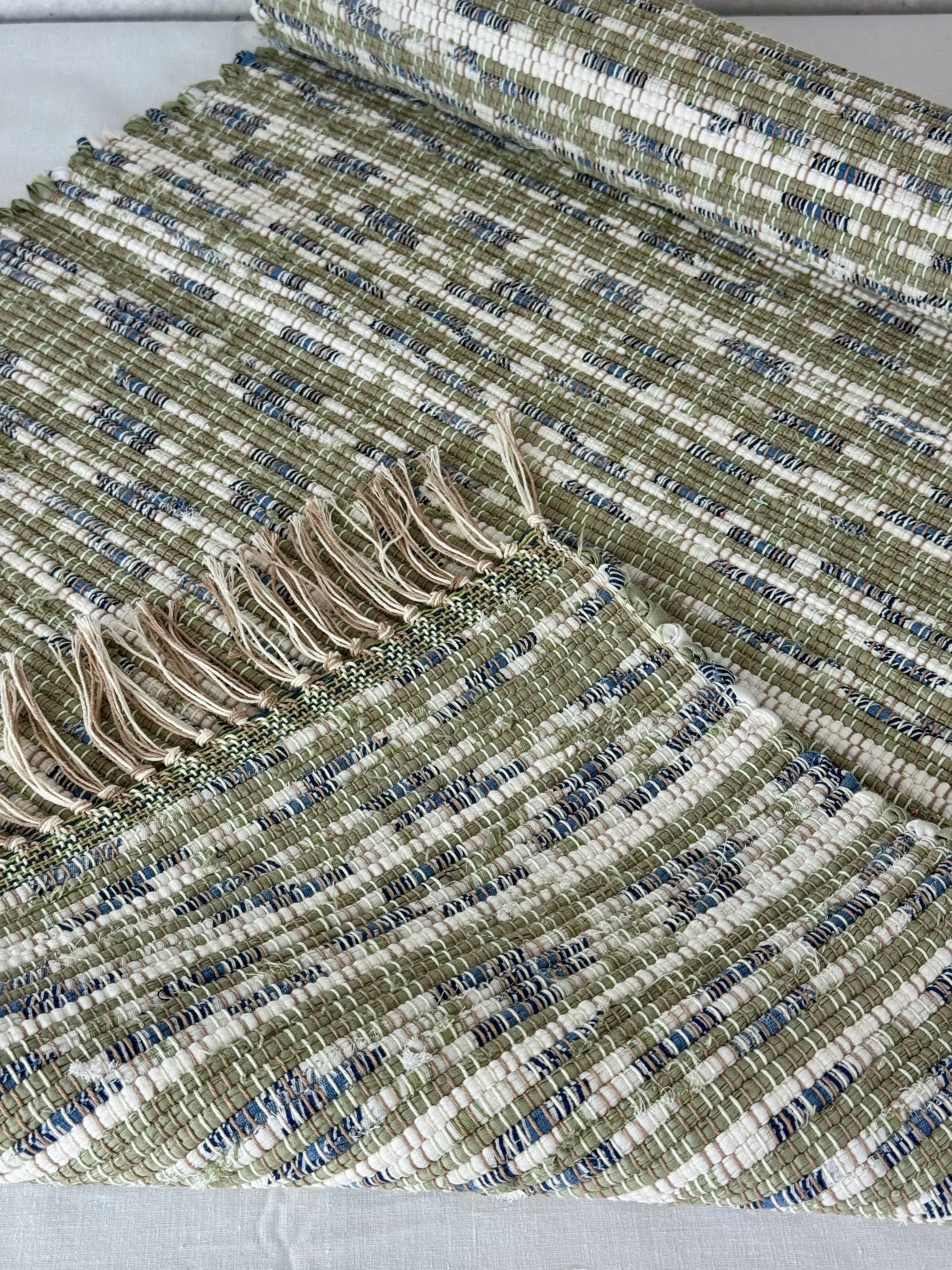 Folded handwoven rag rug showing reverse side and fringe