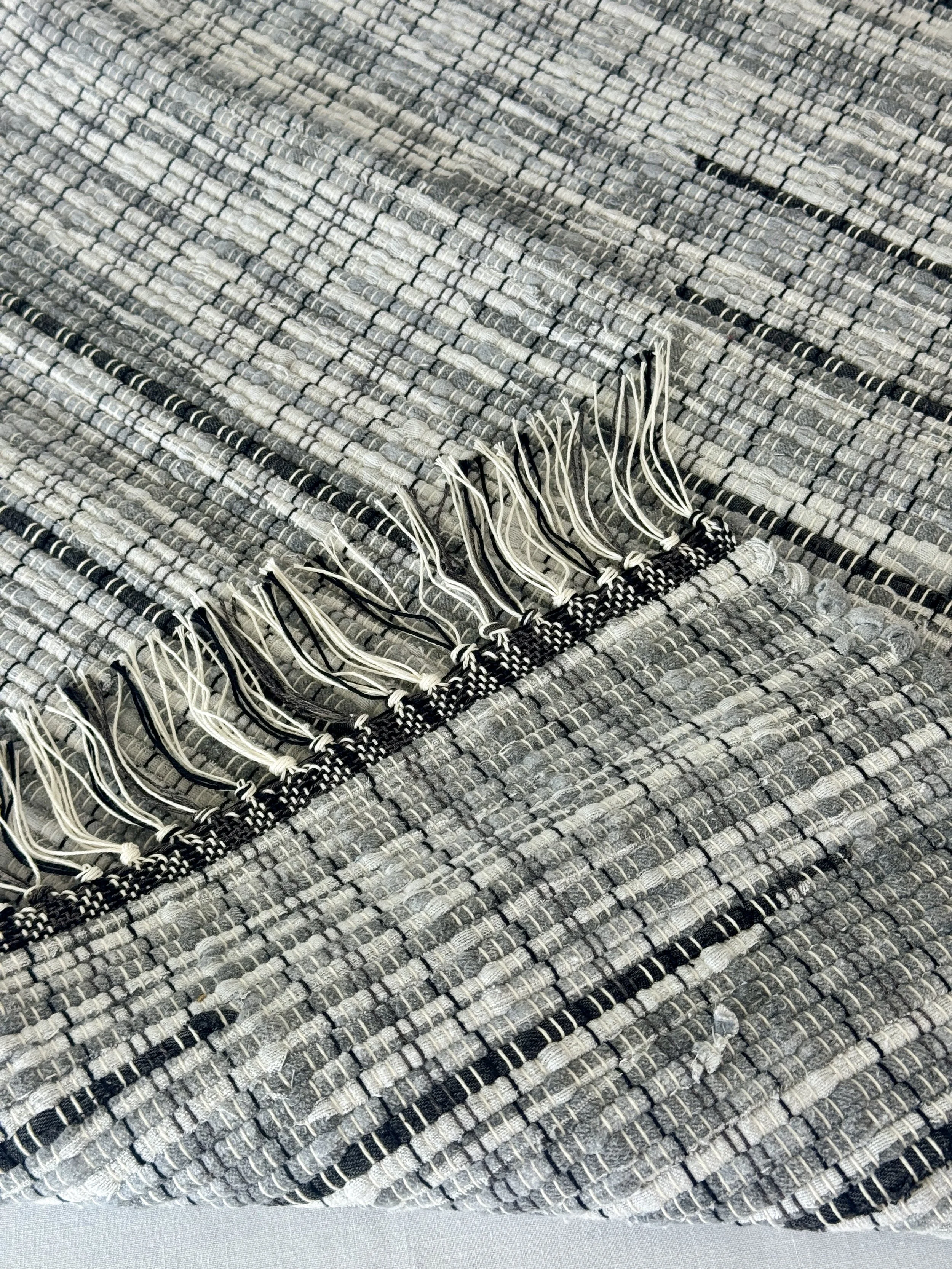 Folded handwoven rag rug showing reverse side and fringe