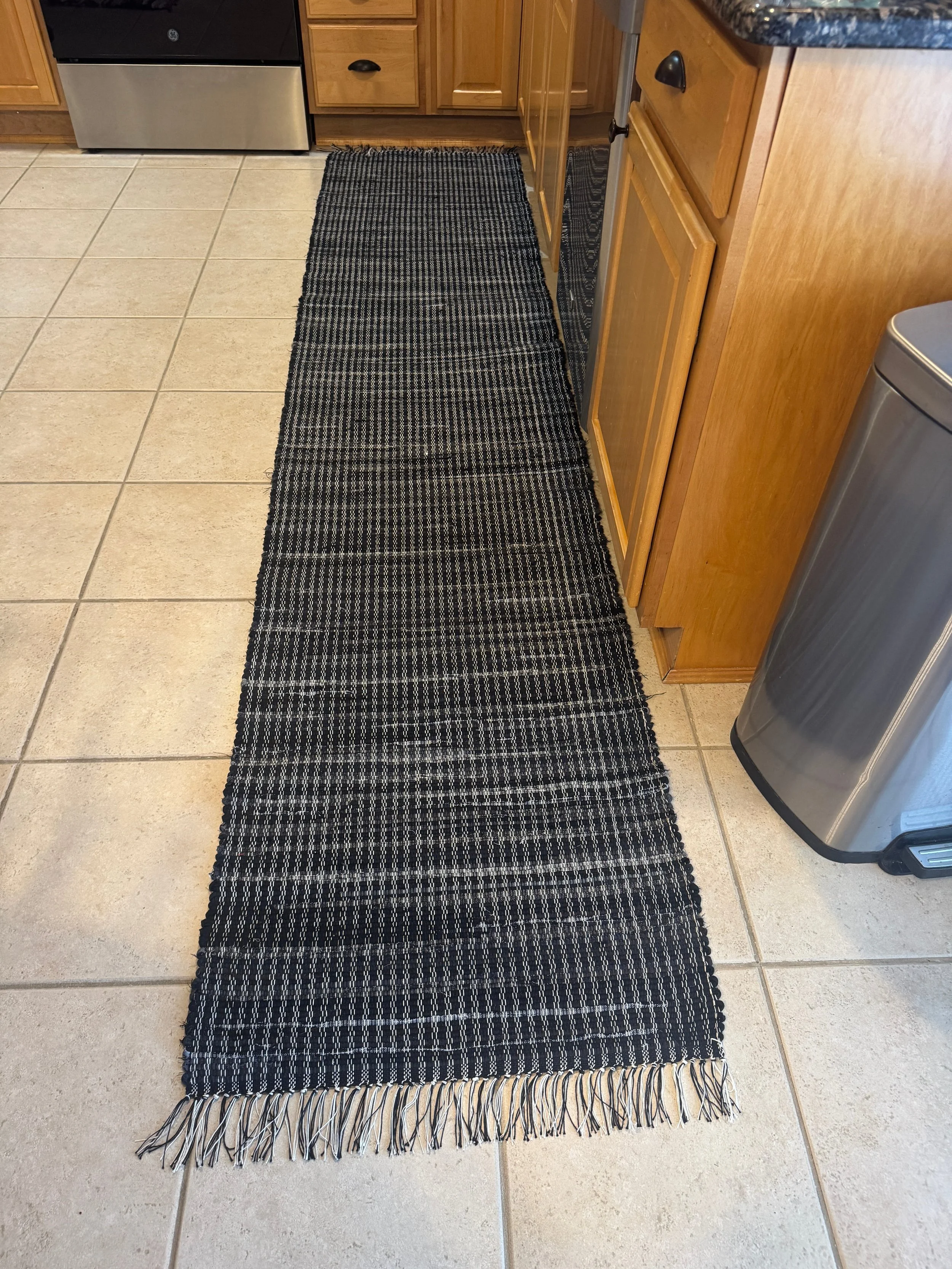 Black handwoven rag rug displayed on kitchen floor showing full pattern