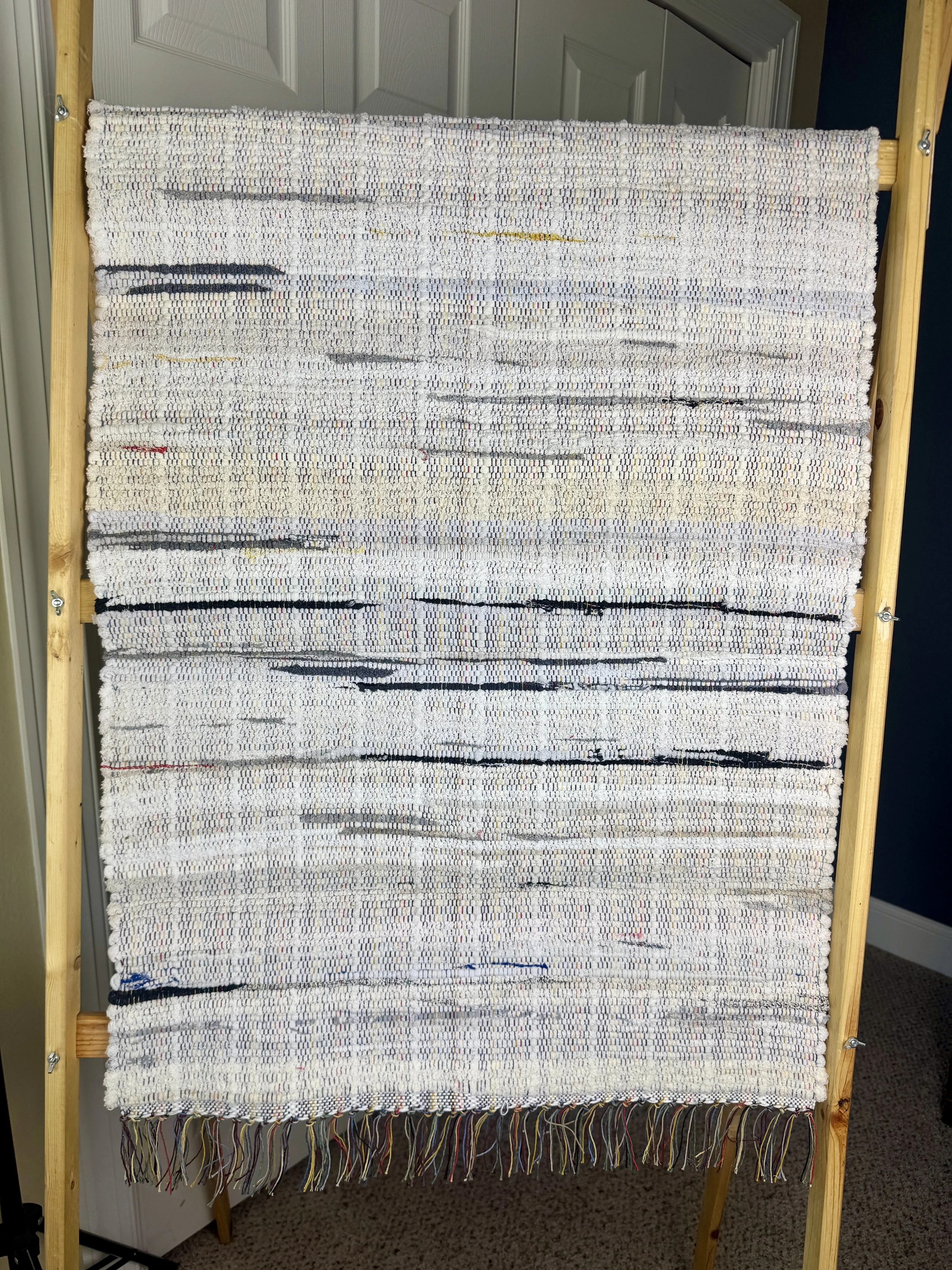 Hanging handmade recycled cotton  rag rug showing pattern and fringe