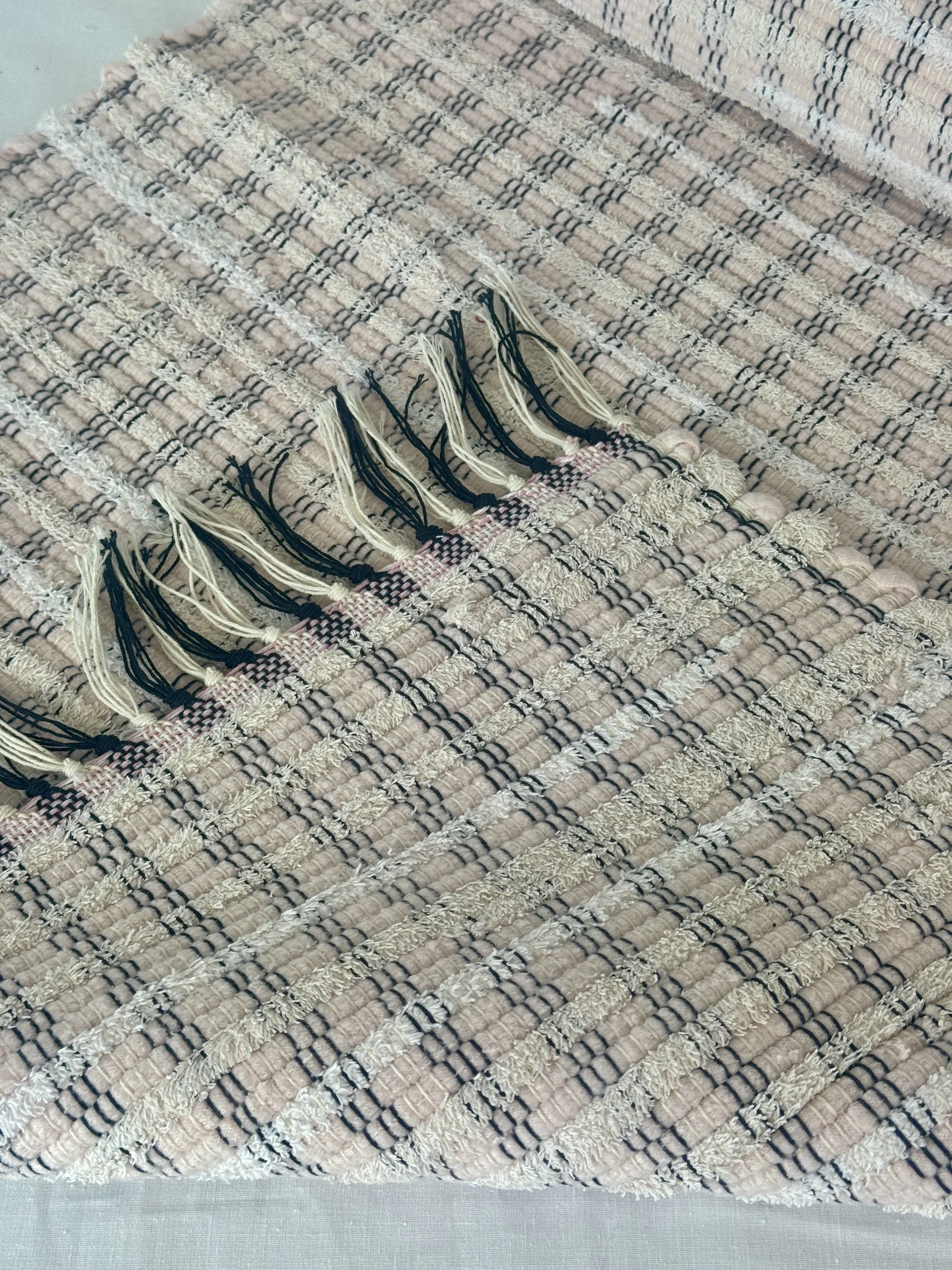 Folded handwoven rag rug showing reverse side and fringe