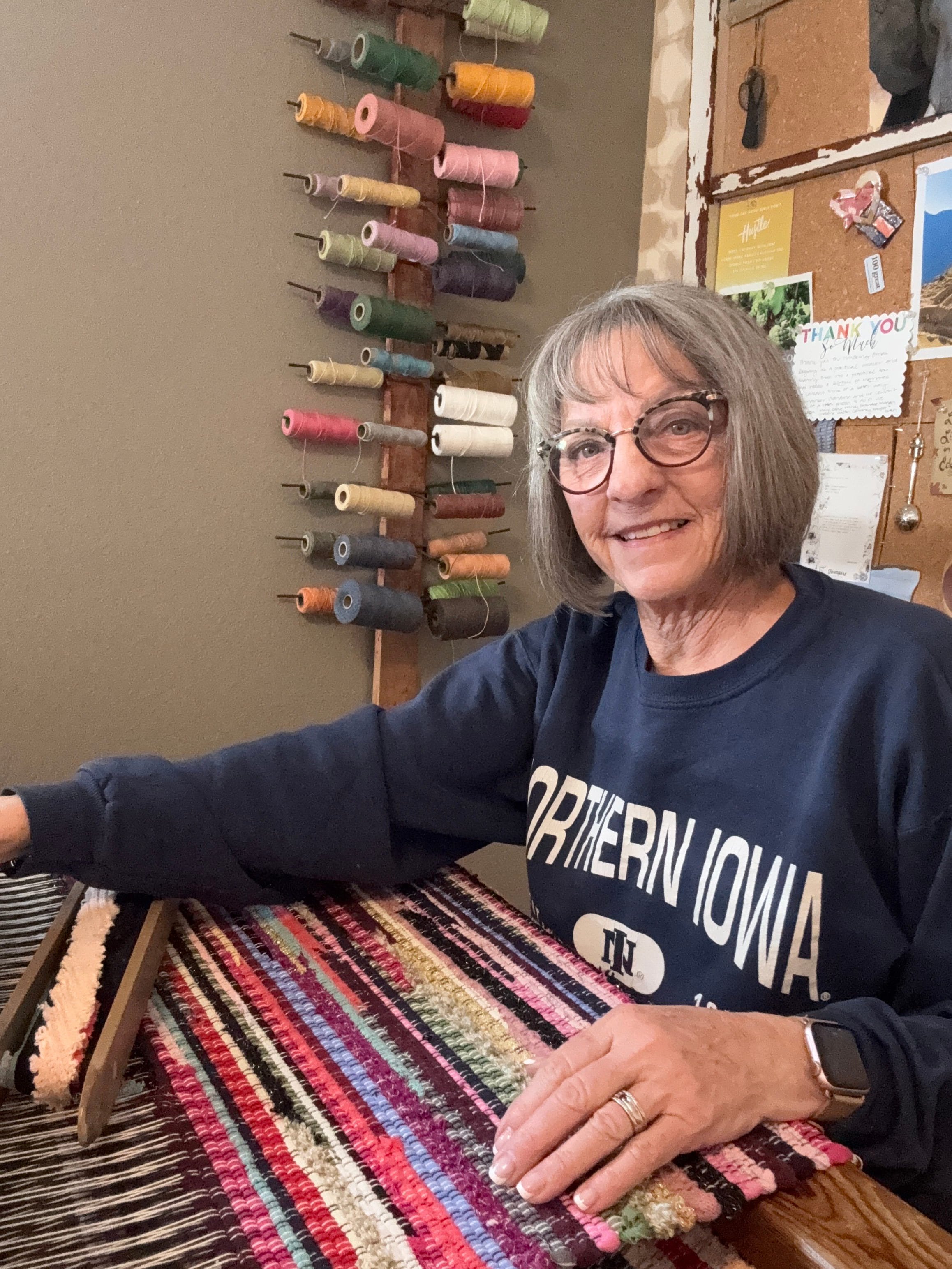 Terry weaving a handmade rag rug on wooden floor loom in her home