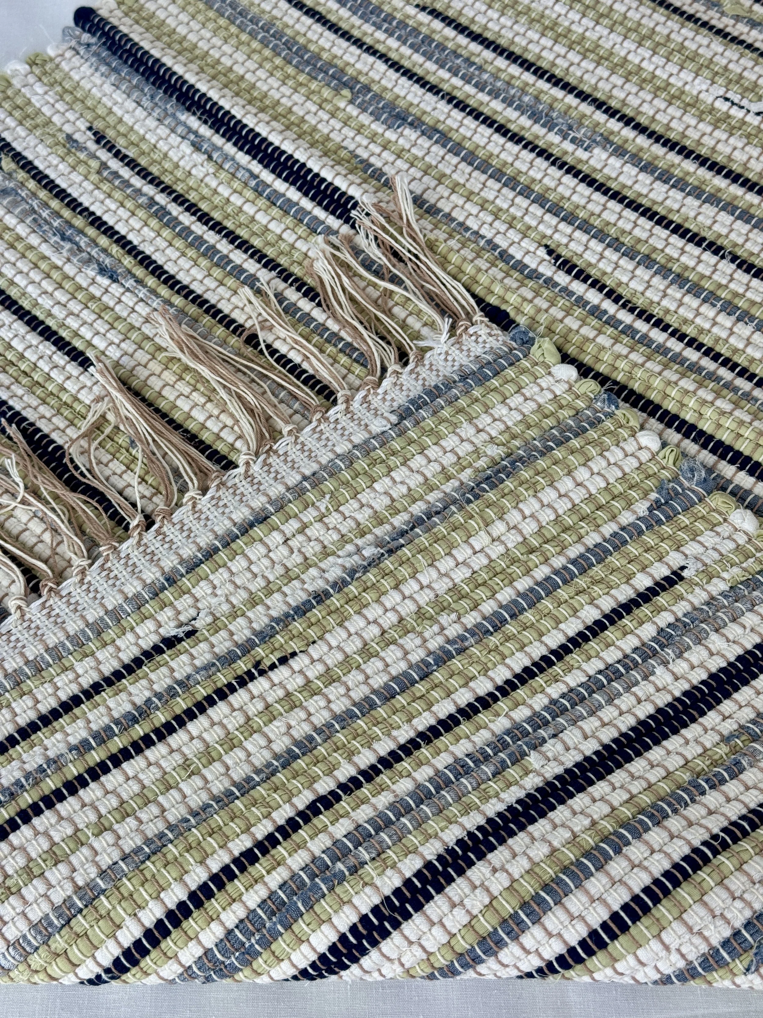 Folded handwoven recycled cotton textiles rag rug showing texture and fringe