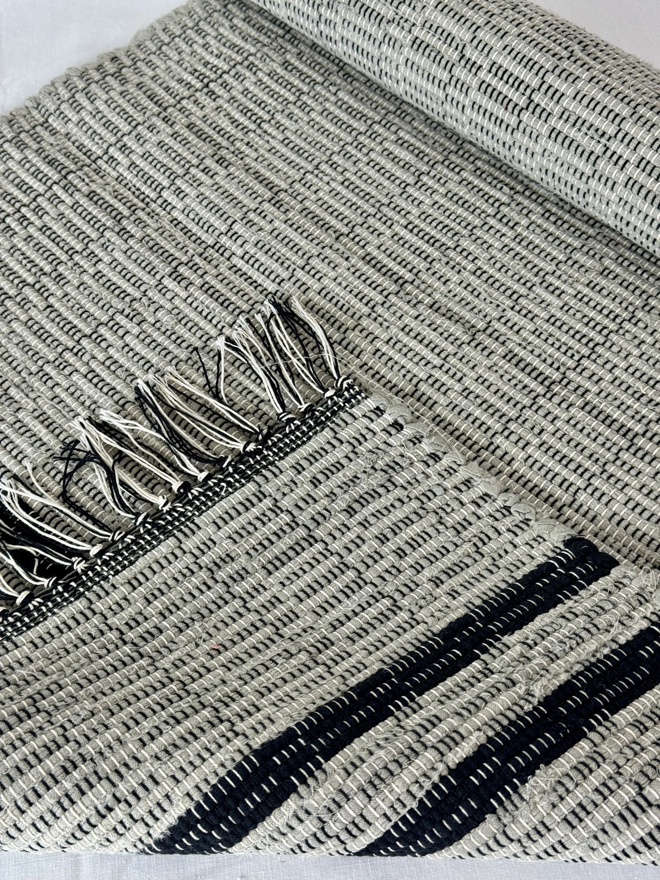 Folded handmade rug showing reverse side and fringe