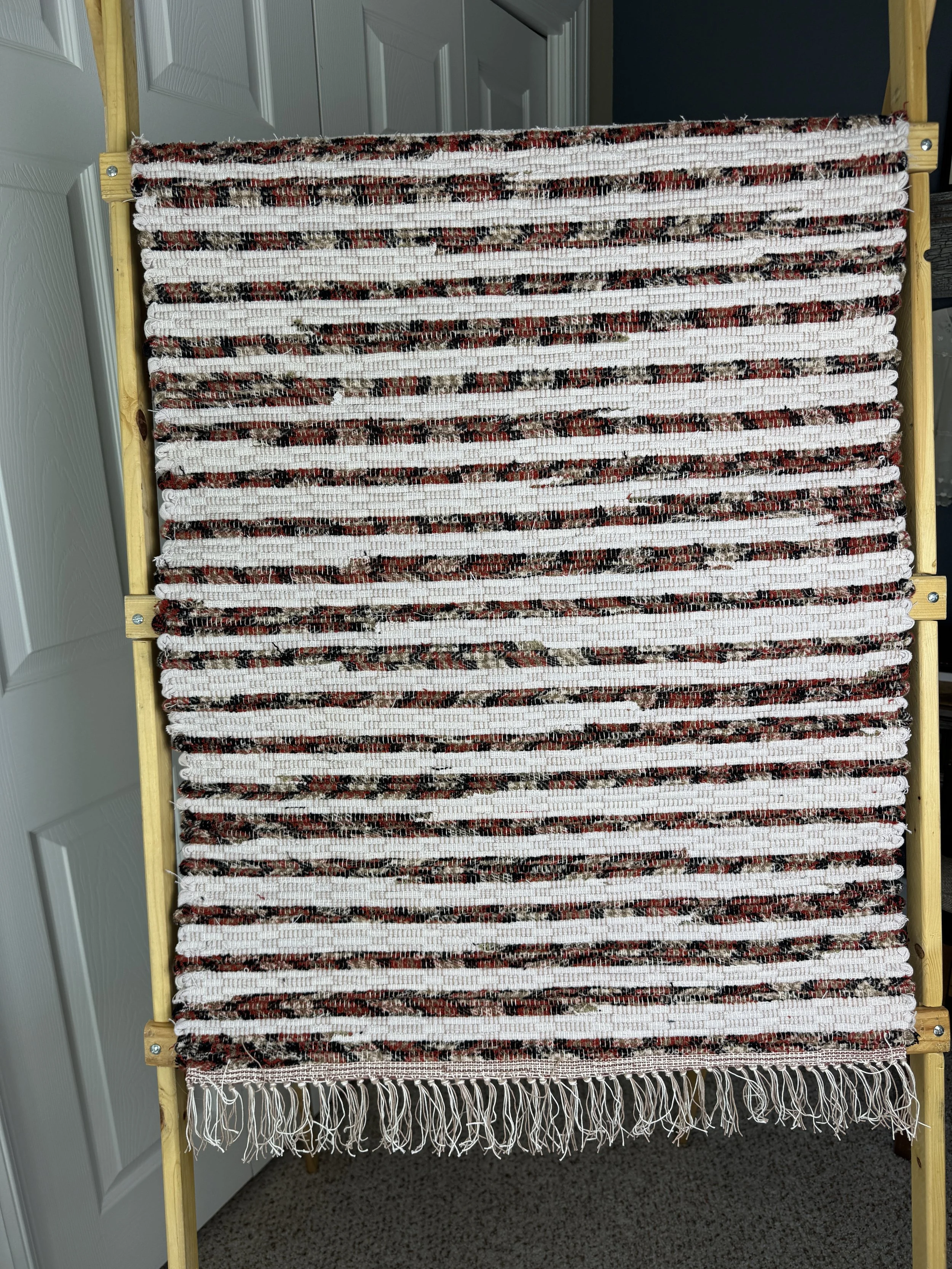Hanging handmade recycled cotton blends rag rug showing pattern and fringe