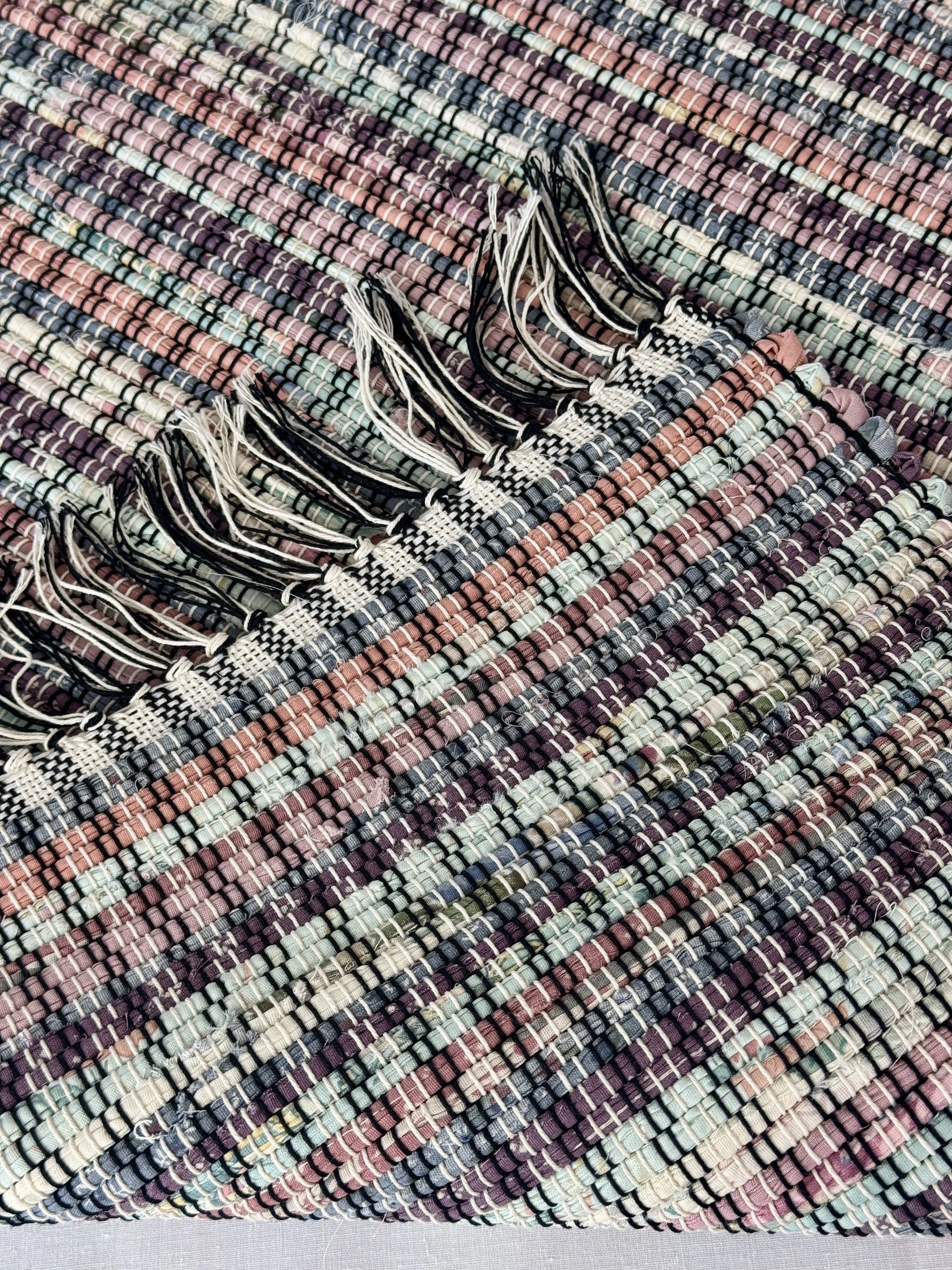 Folded handwoven recycled cotton textiles rag rug showing texture and fringe
