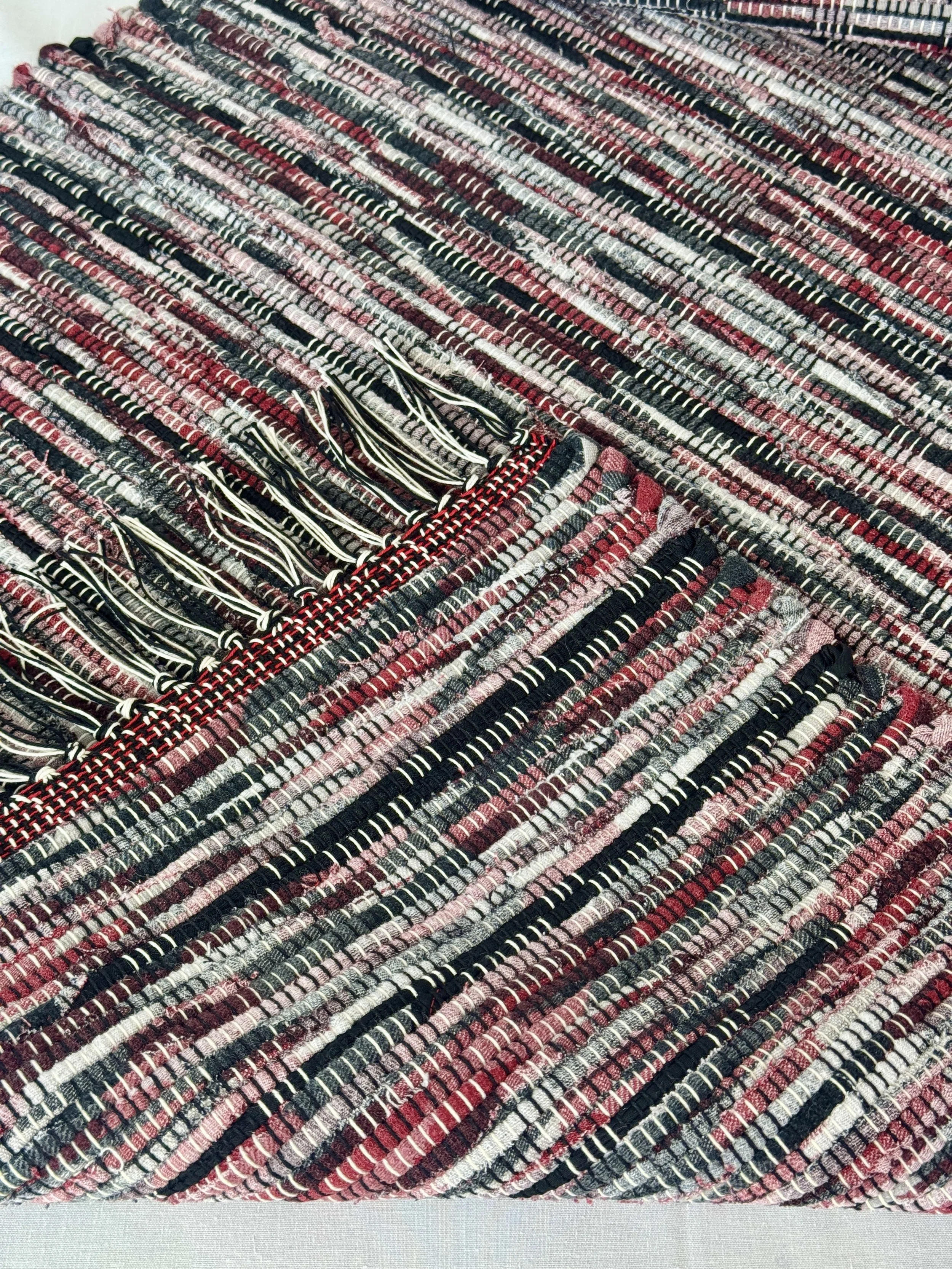 Folded handwoven rag rug showing reverse side and fringe