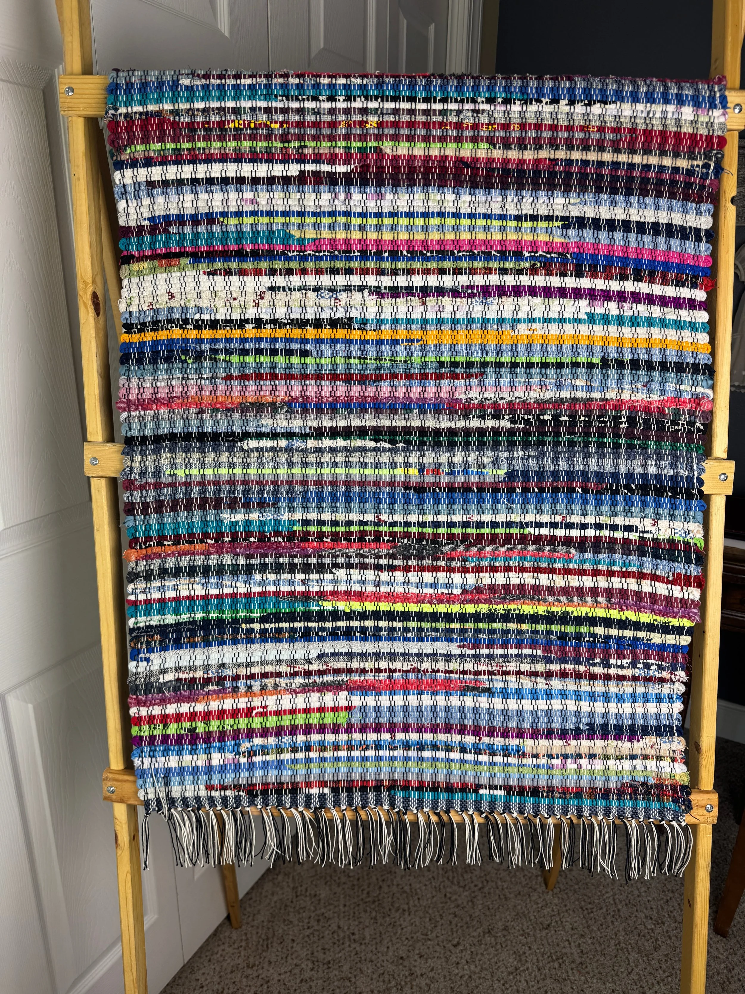 Hanging handmade recycled cotton blends rag rug showing pattern and fringe