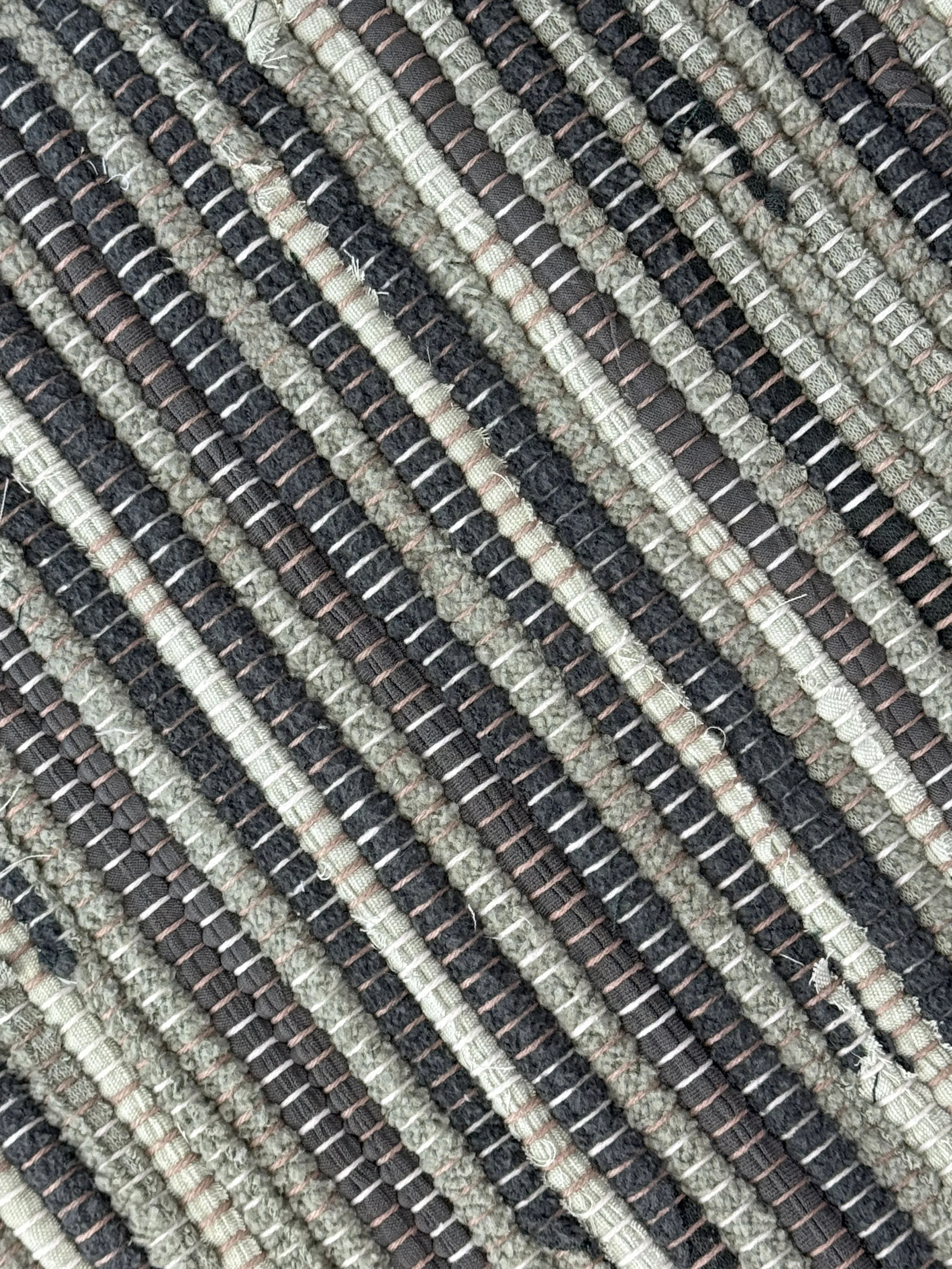 Up close handmade rag rug of upcycled cotton blend textiles showing texture and weave