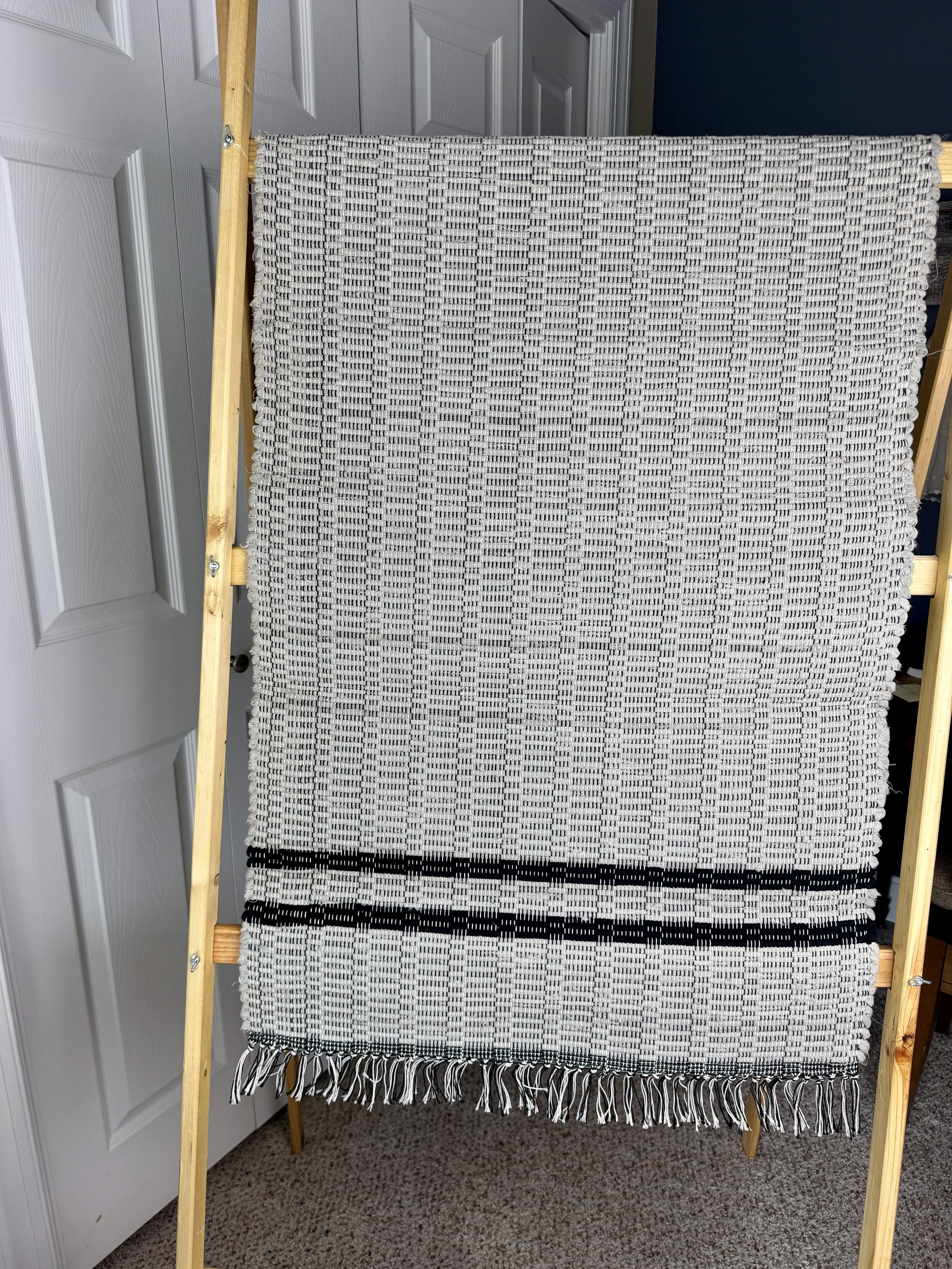 Hanging handmade recycled cotton  rag rug showing pattern and fringe