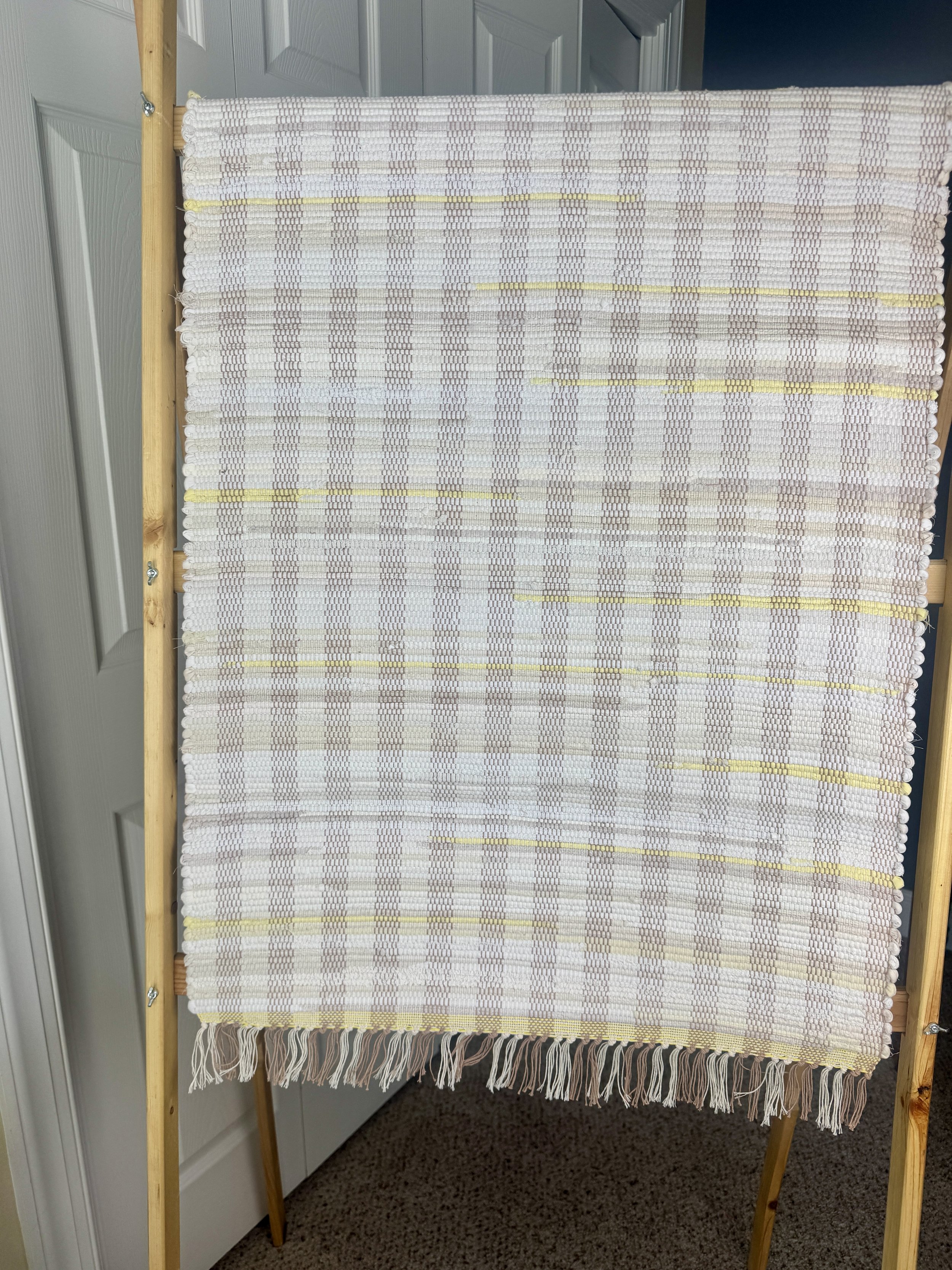 Hanging handmade recycled cotton  rag rug showing pattern and fringe