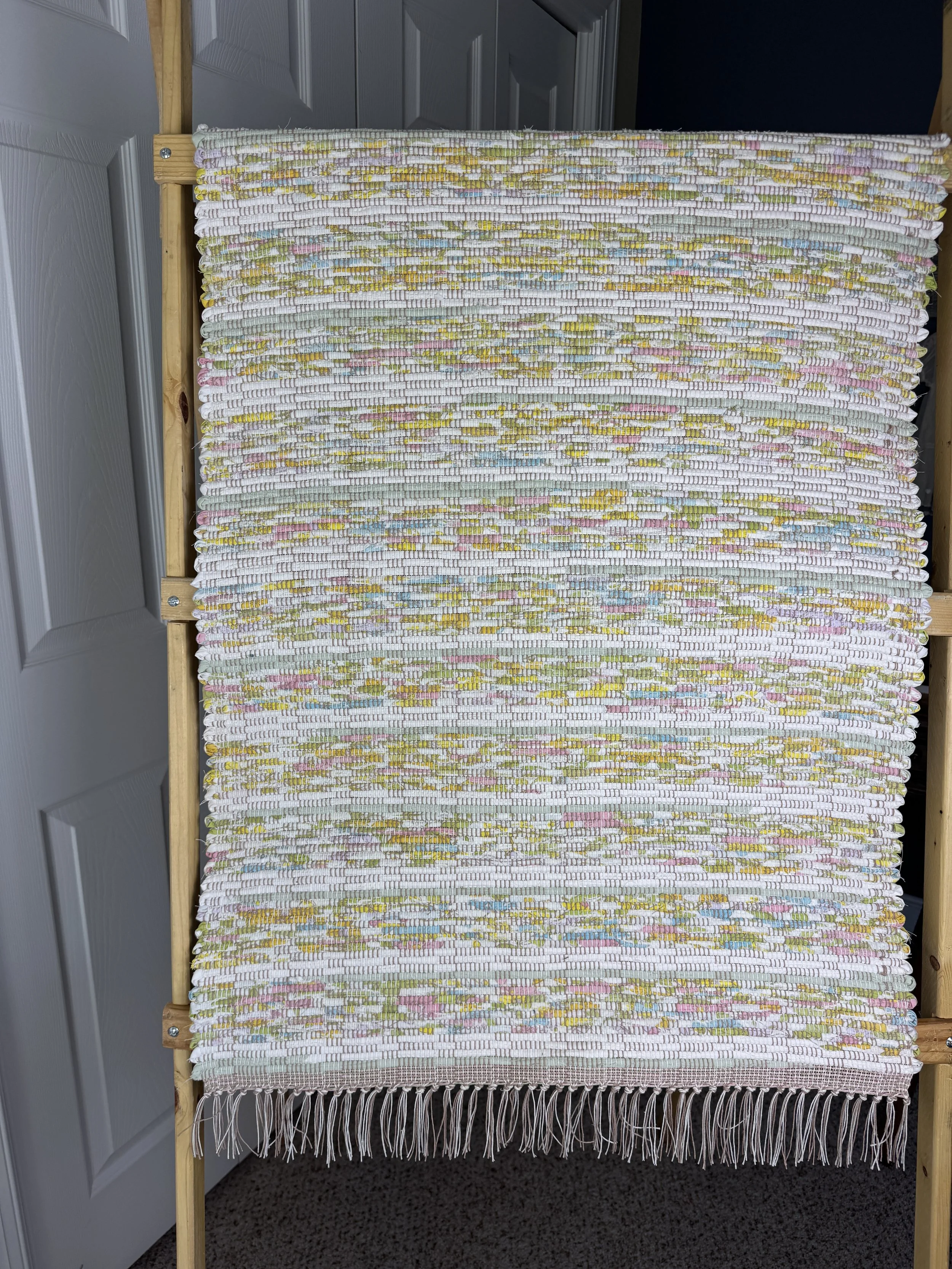 Hanging handmade recycled cotton blends rag rug showing pattern and fringe