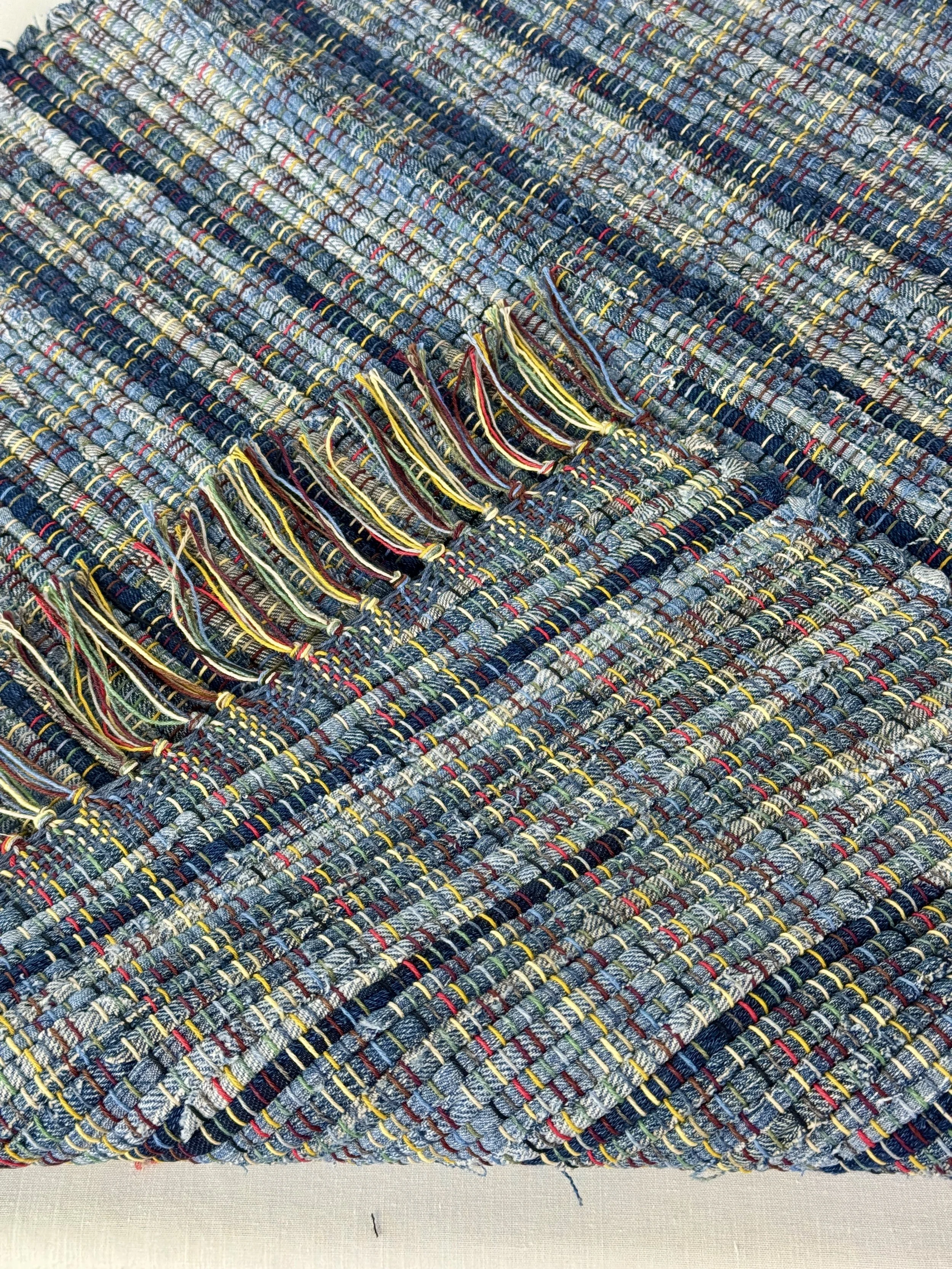 Folded handmade rug showing reverse side and fringe