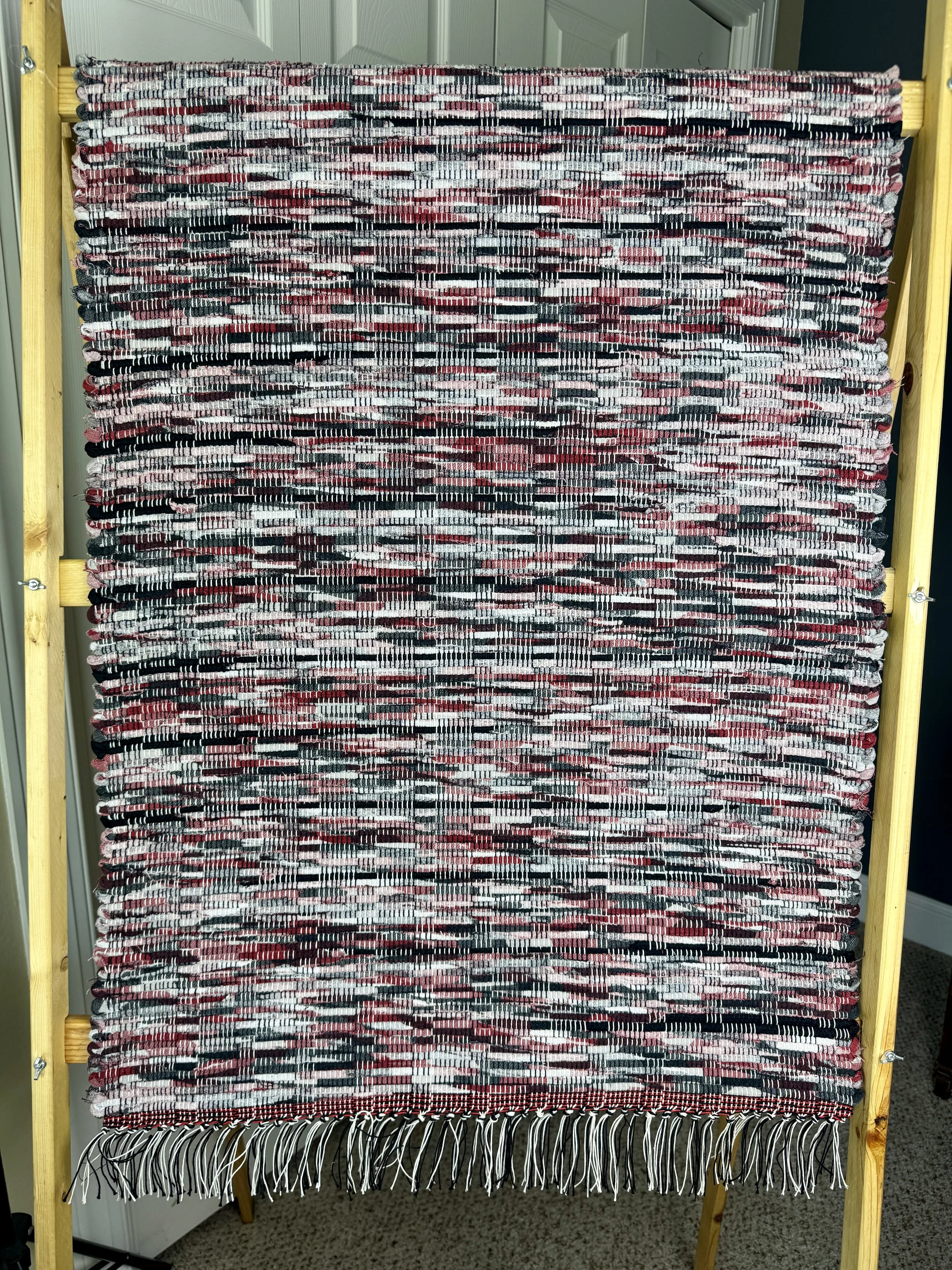 Hanging handmade recycled cotton blends rag rug showing pattern and fringe