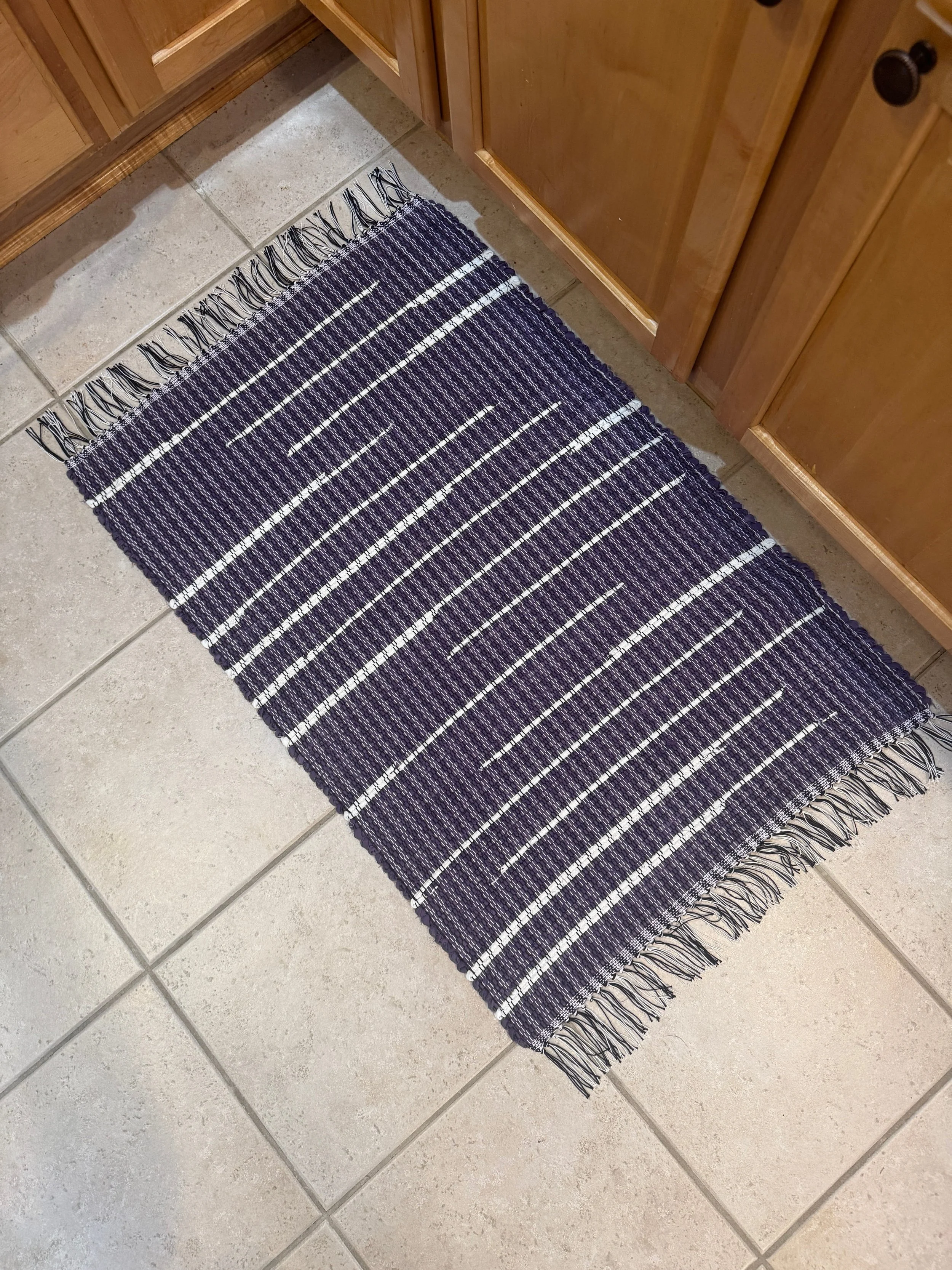 Handwoven purple/white woven rag rug displayed in kitchen showing pattern