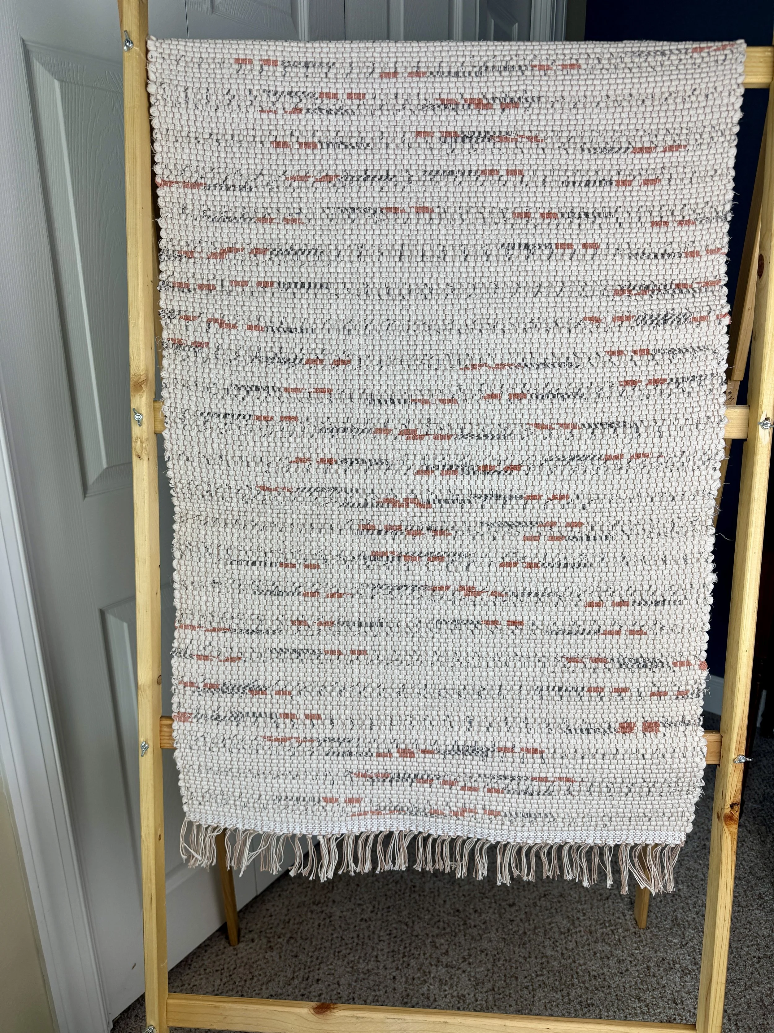 Hanging handmade recycled cotton rag rug showing pattern and fringe