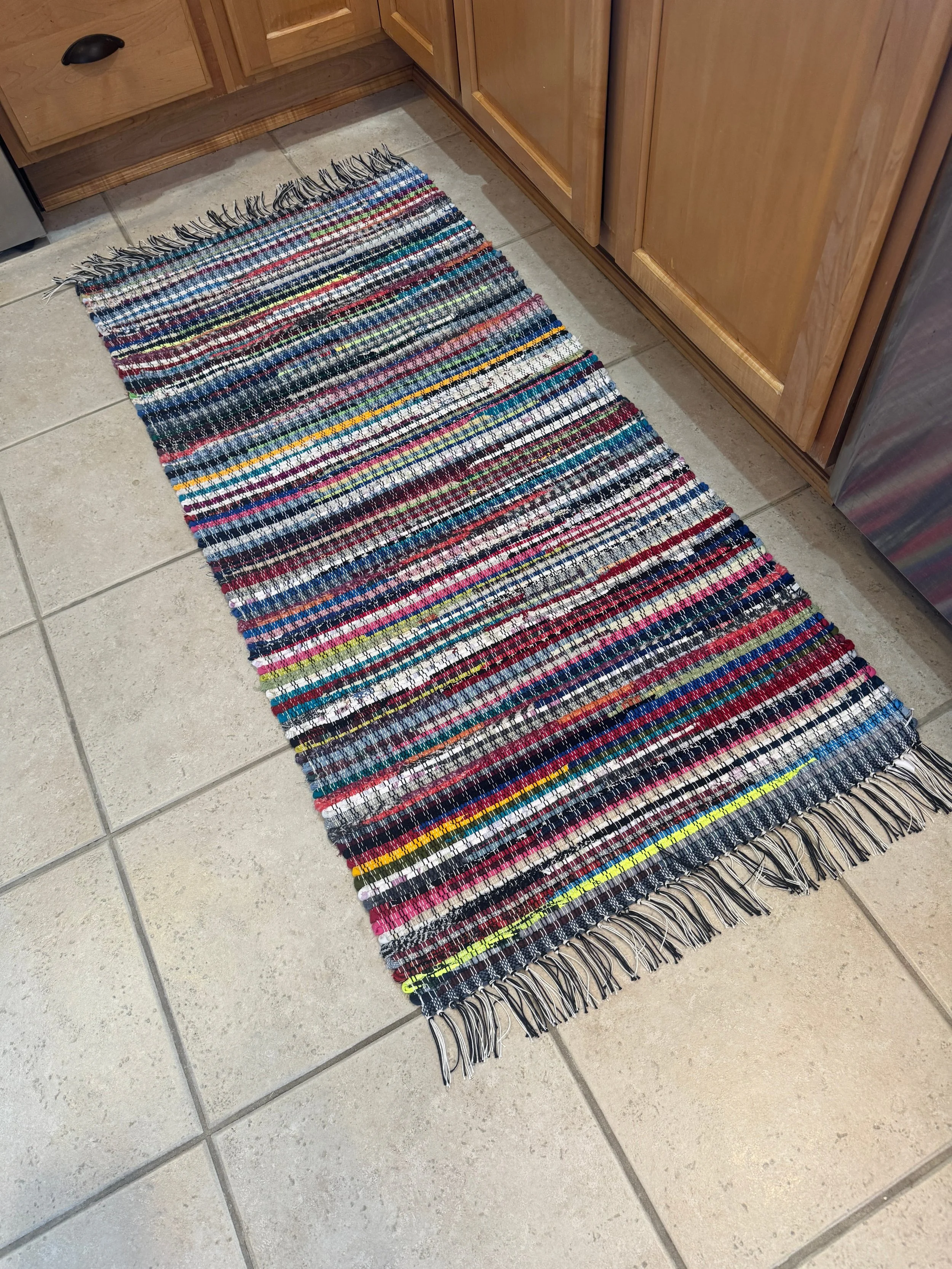 Handmade rag rug woven on wooden floor loom displayed in kitchen showing full pattern