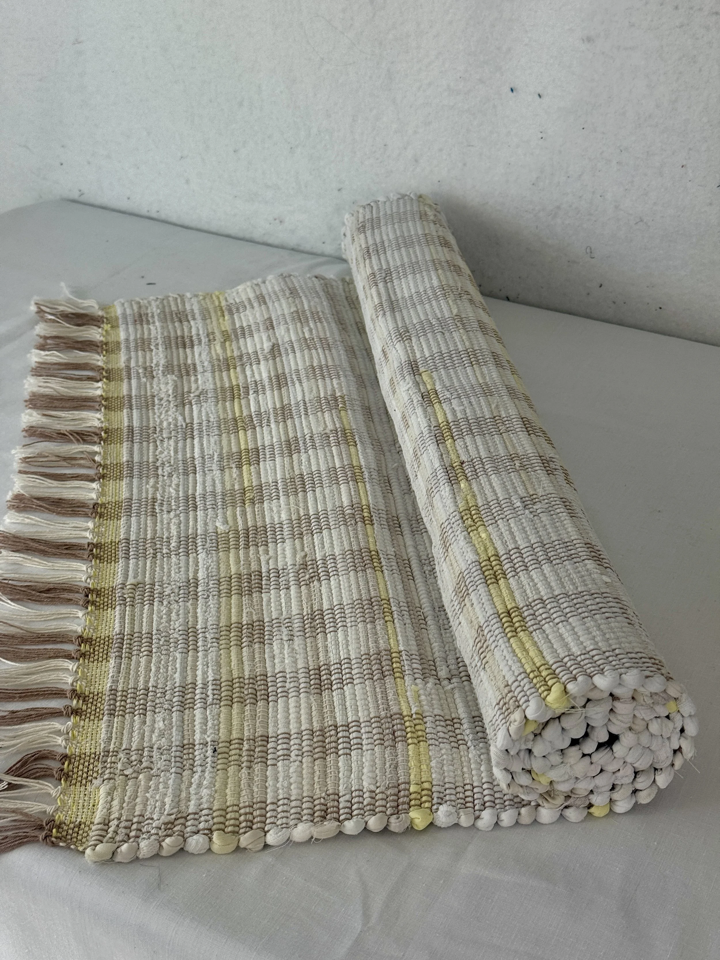 Handwoven white with yellow accents rag rug made from recycled textiles
