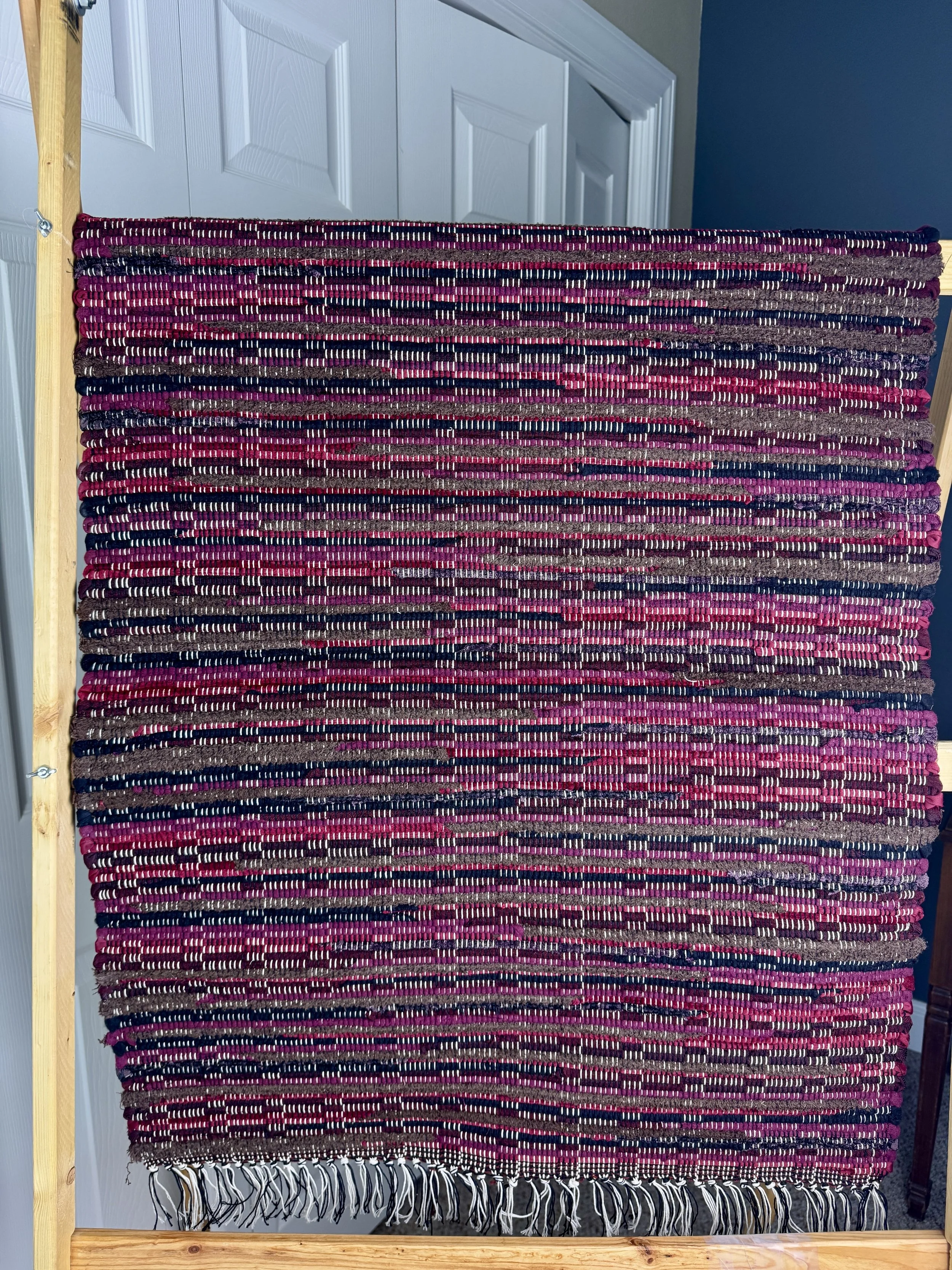 Hanging handmade recycled cotton blends rag rug showing pattern and fringe