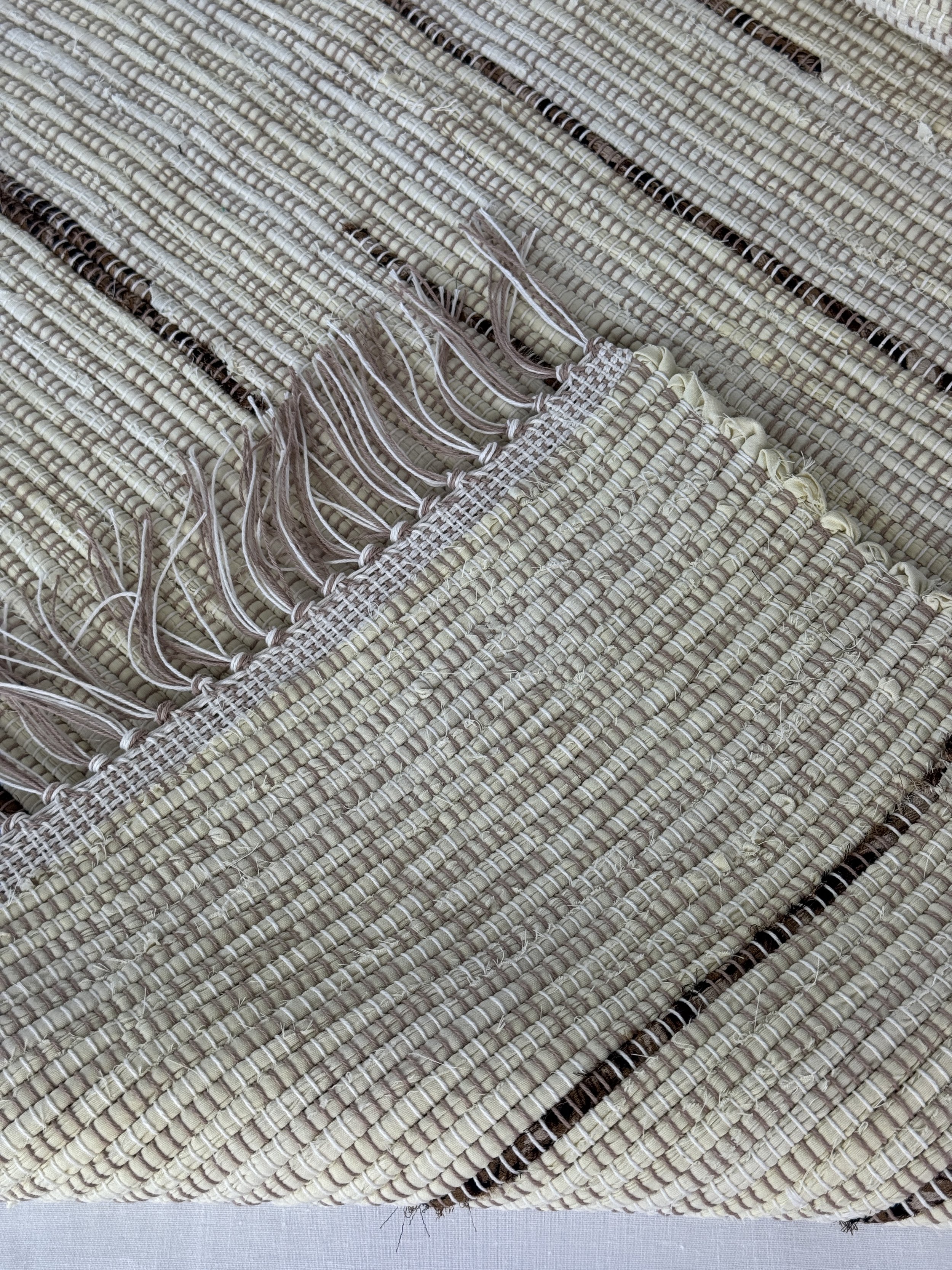 Folded handwoven rag rug showing reverse side and fringe
