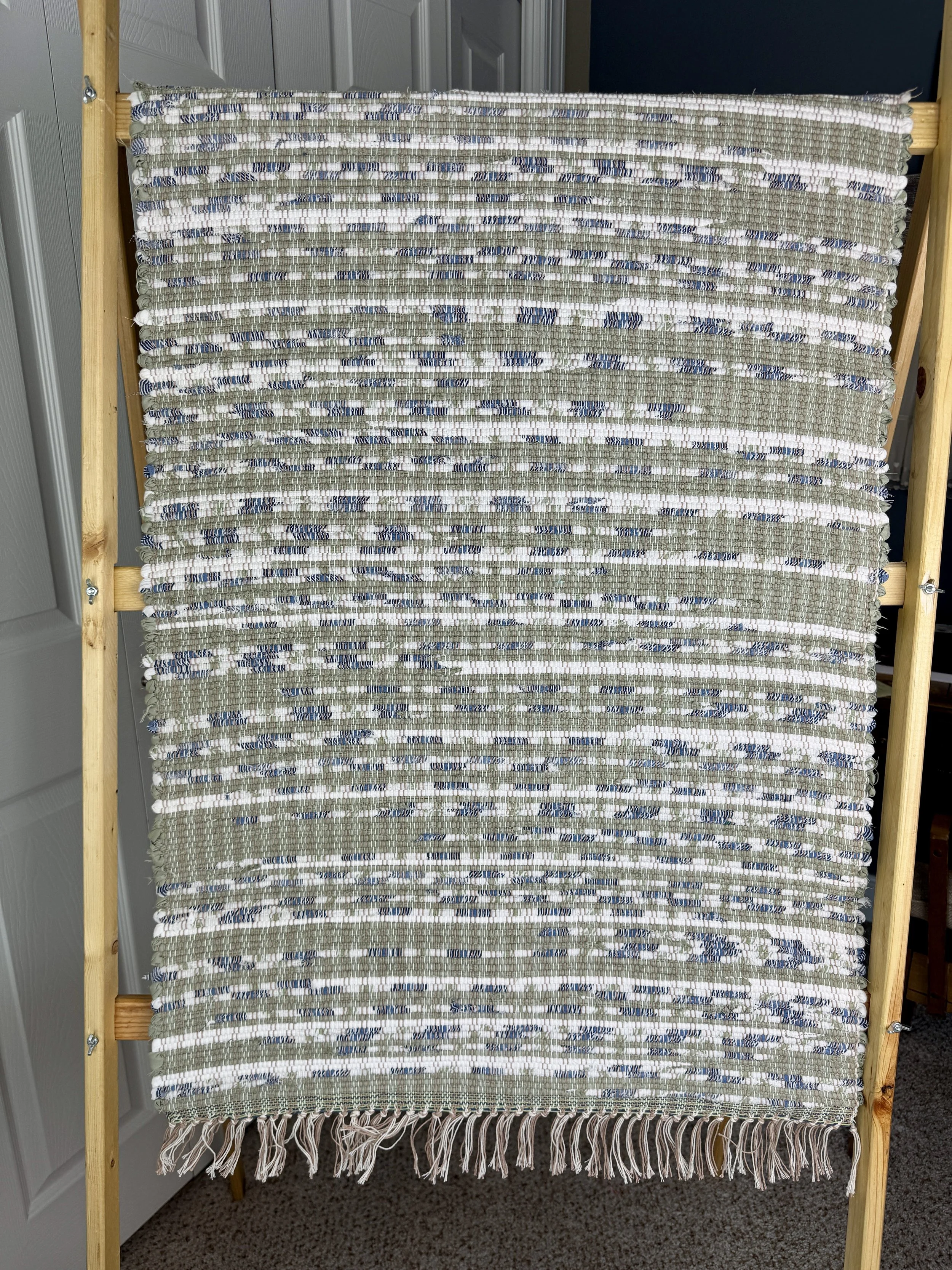 Hanging handmade recycled cotton  rag rug showing pattern and fringe