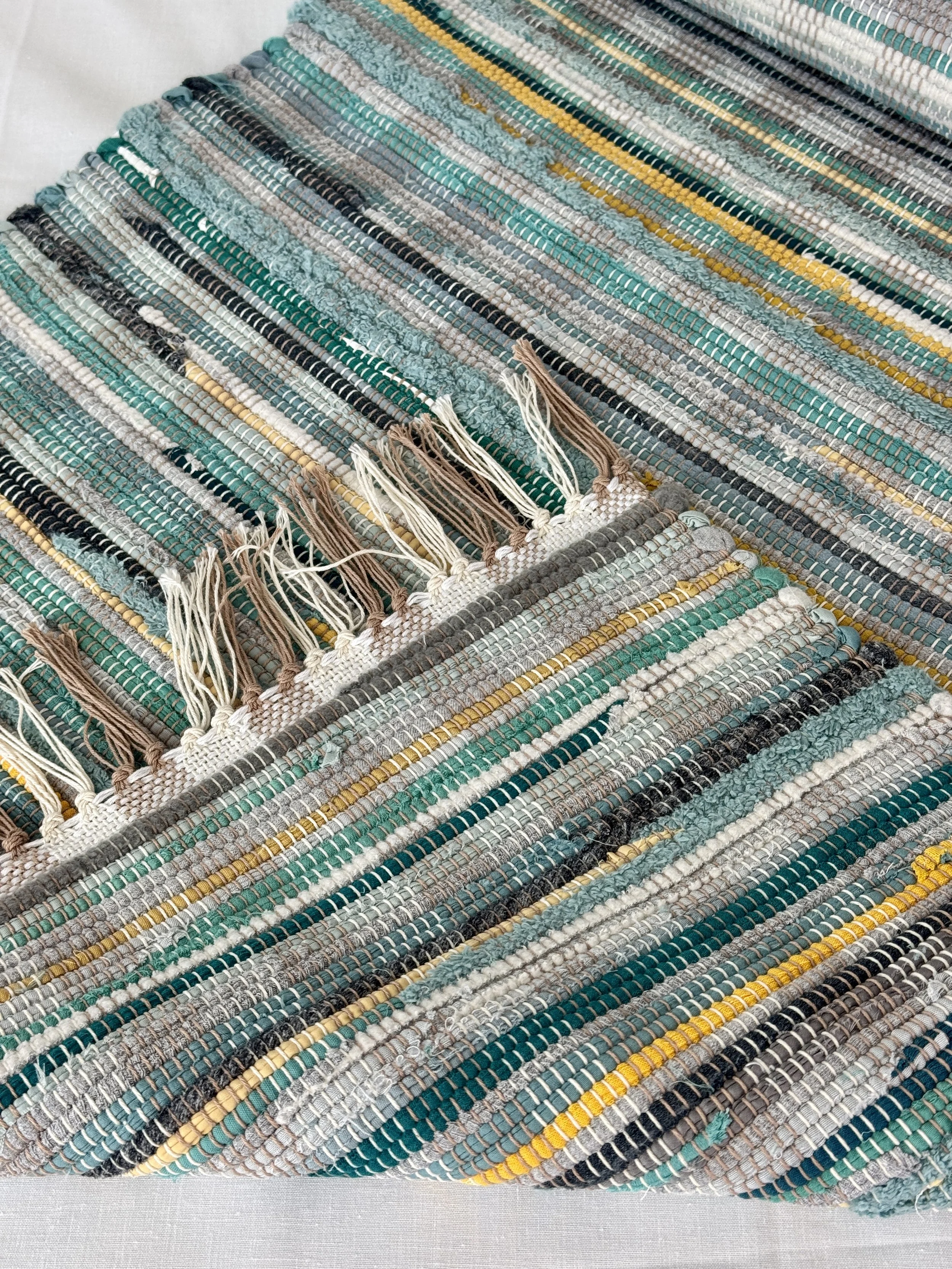 Folded handwoven rag rug showing reverse side and fringe