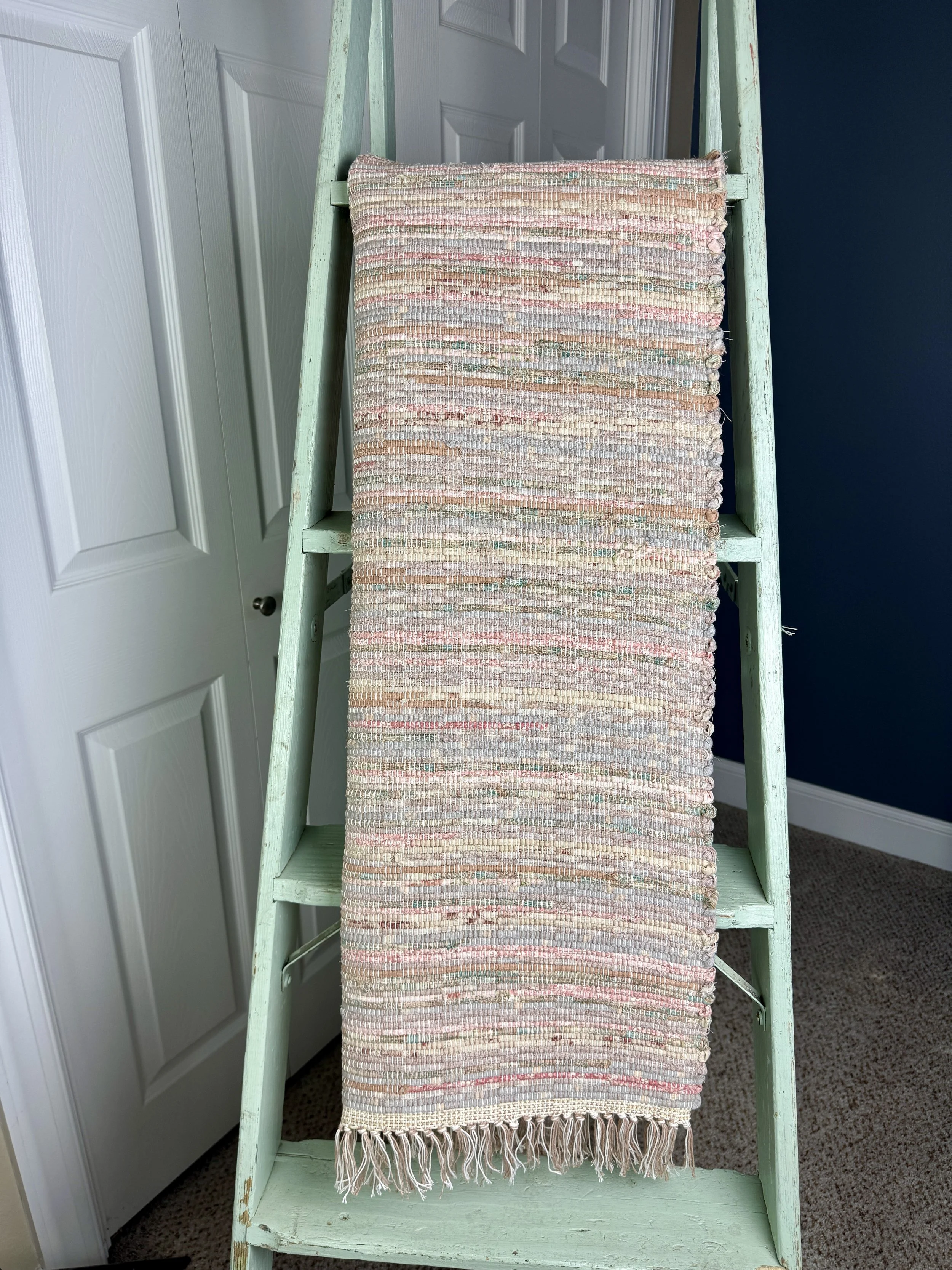 Hanging handmade recycled cotton  rag rug showing pattern and fringe