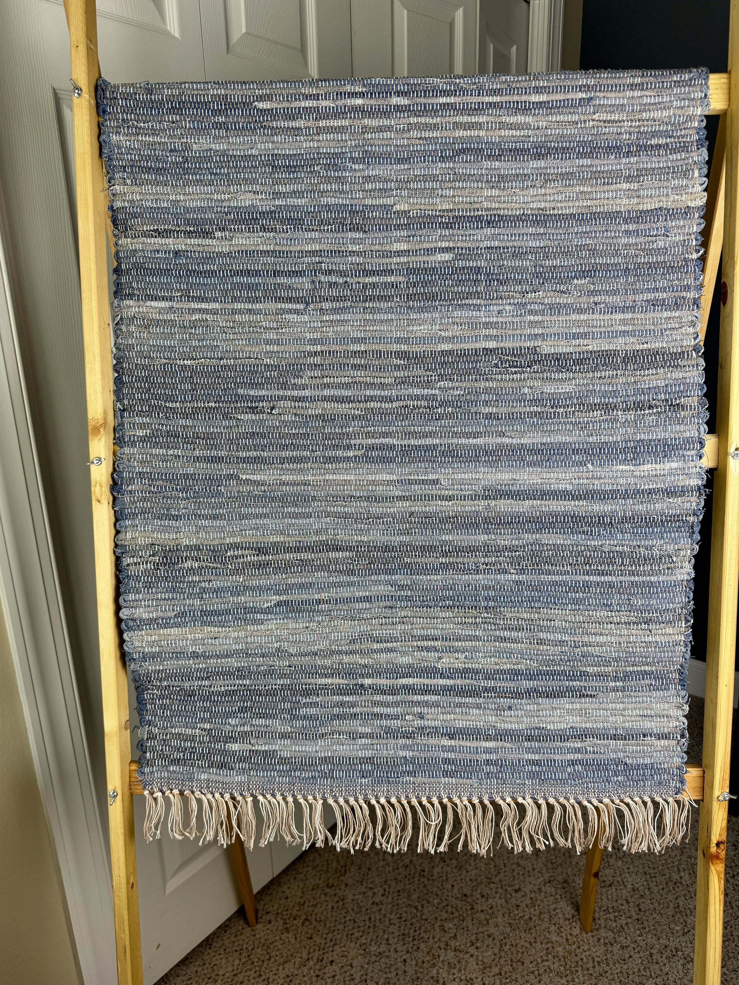 Hanging handmade upcycled denim  rag rug showing pattern and fringe