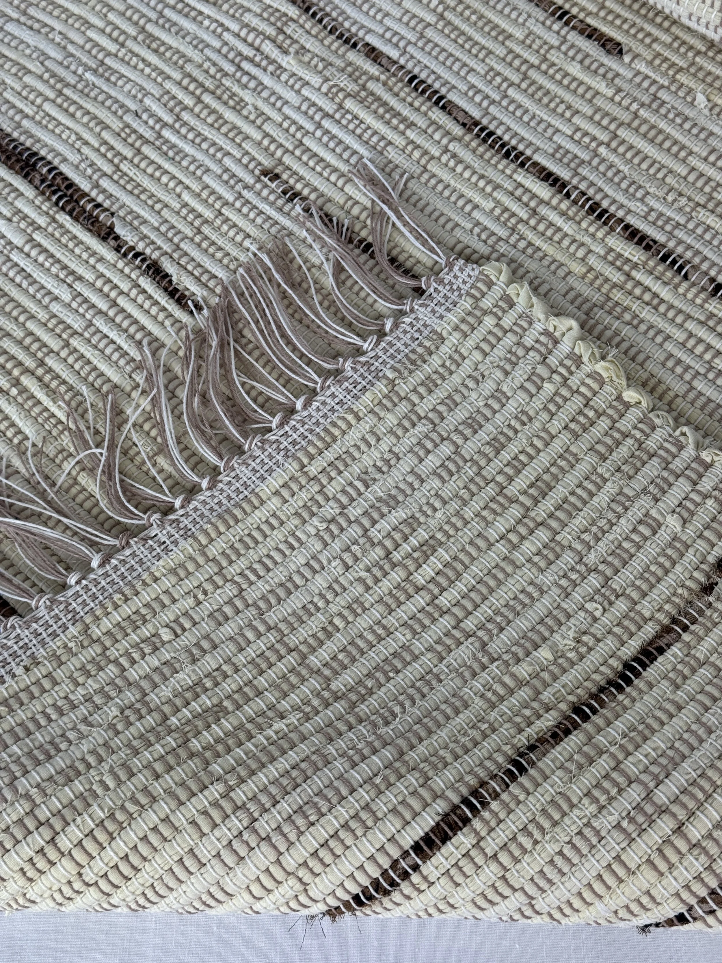 Folded handwoven rag rug showing reverse side and fringe