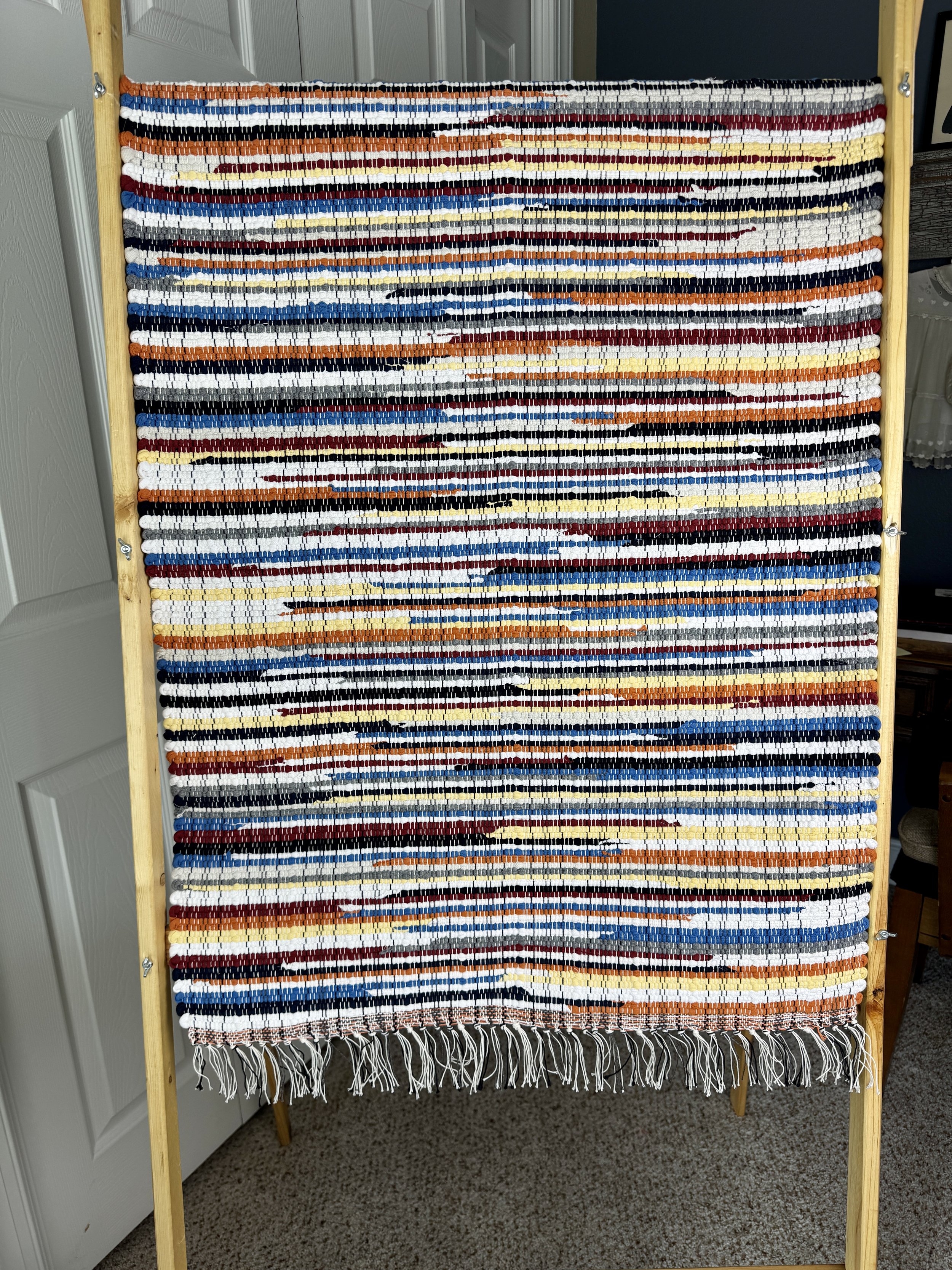 Hanging handmade recycled cotton  rag rug showing pattern and fringe