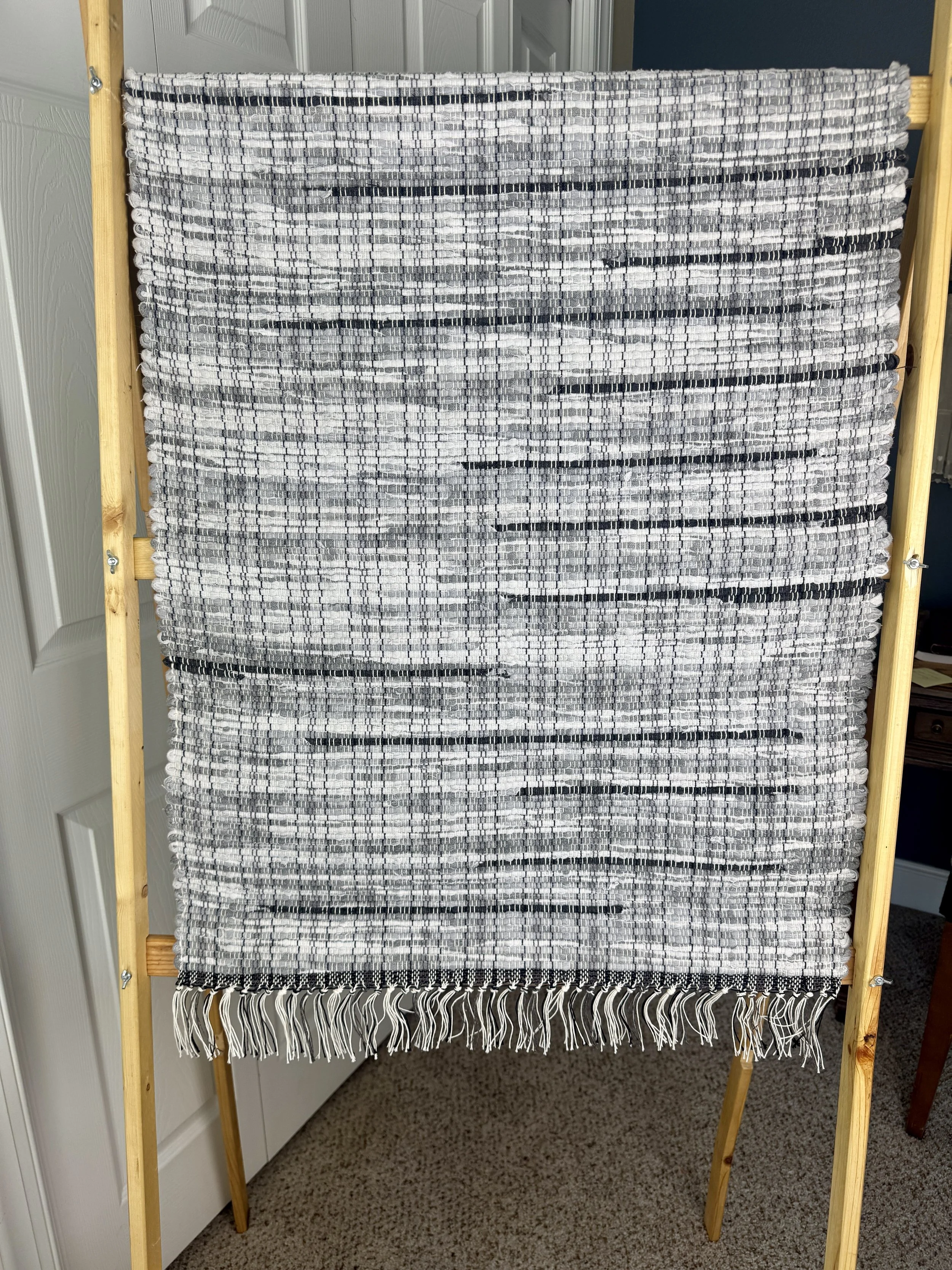 Hanging handmade recycled cotton blends  rag rug showing pattern and fringe