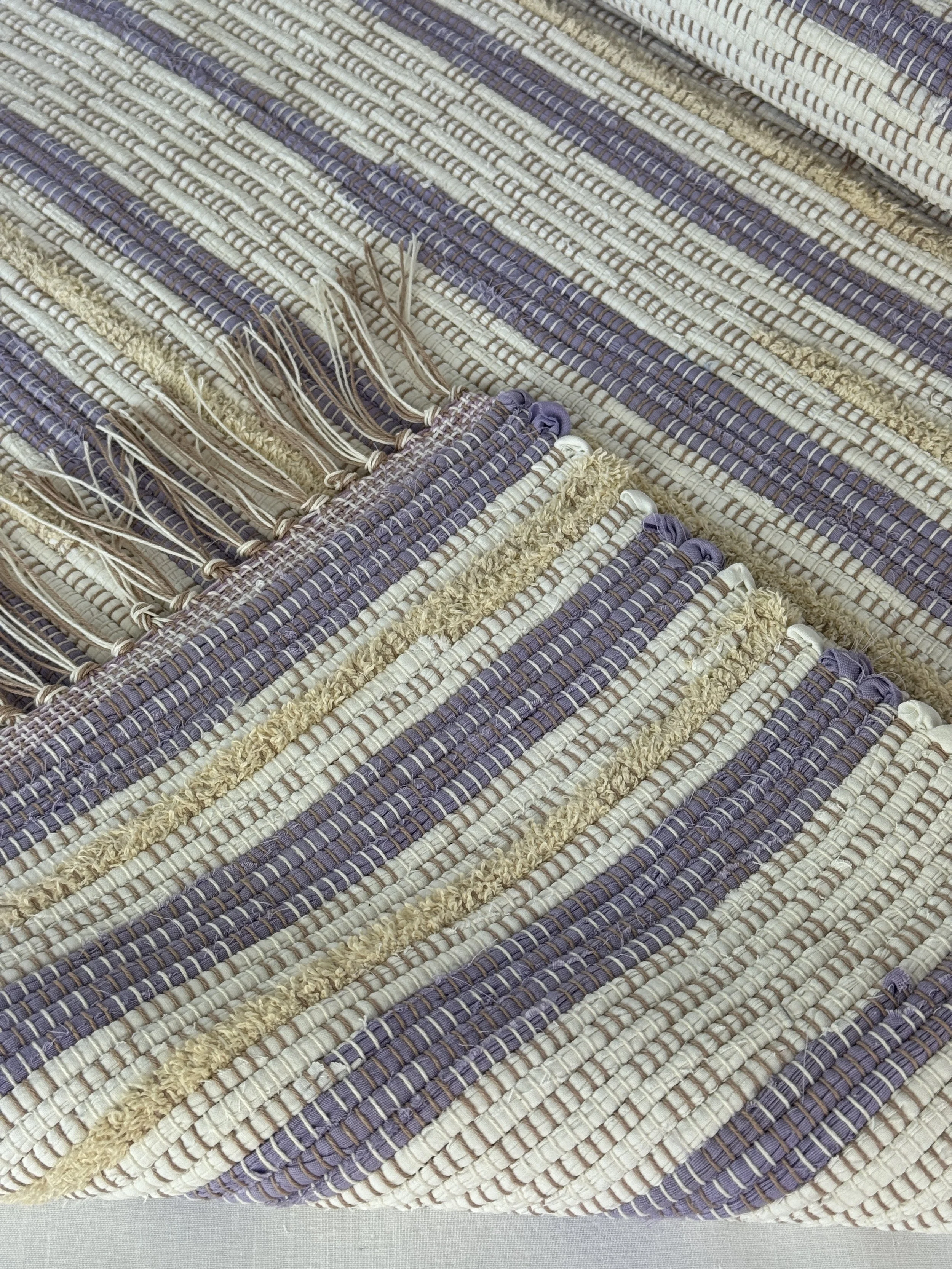 Folded handwoven rag rug showing reverse side and fringe