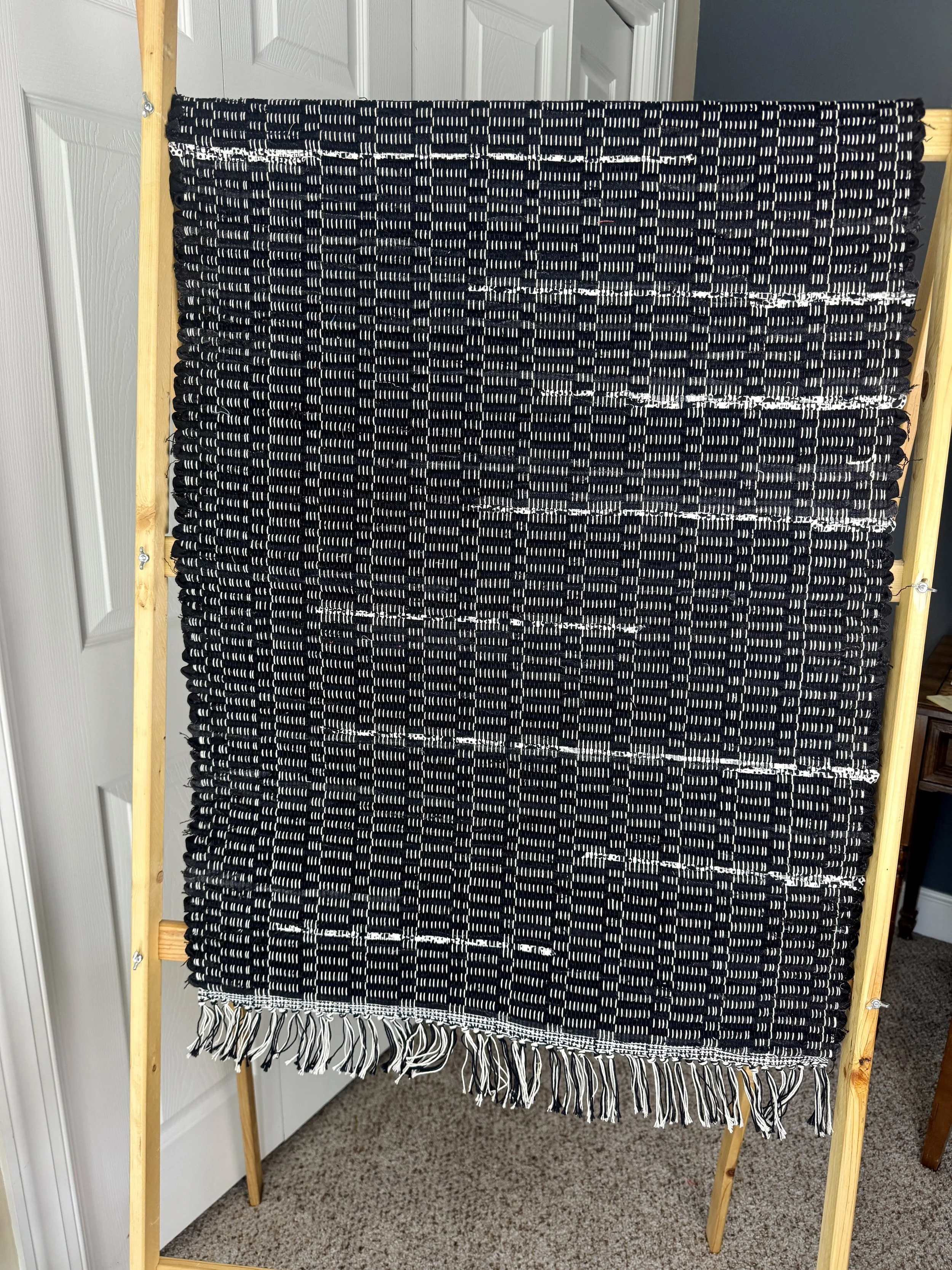 Hanging handmade recycled cotton  rag rug showing pattern and fringe