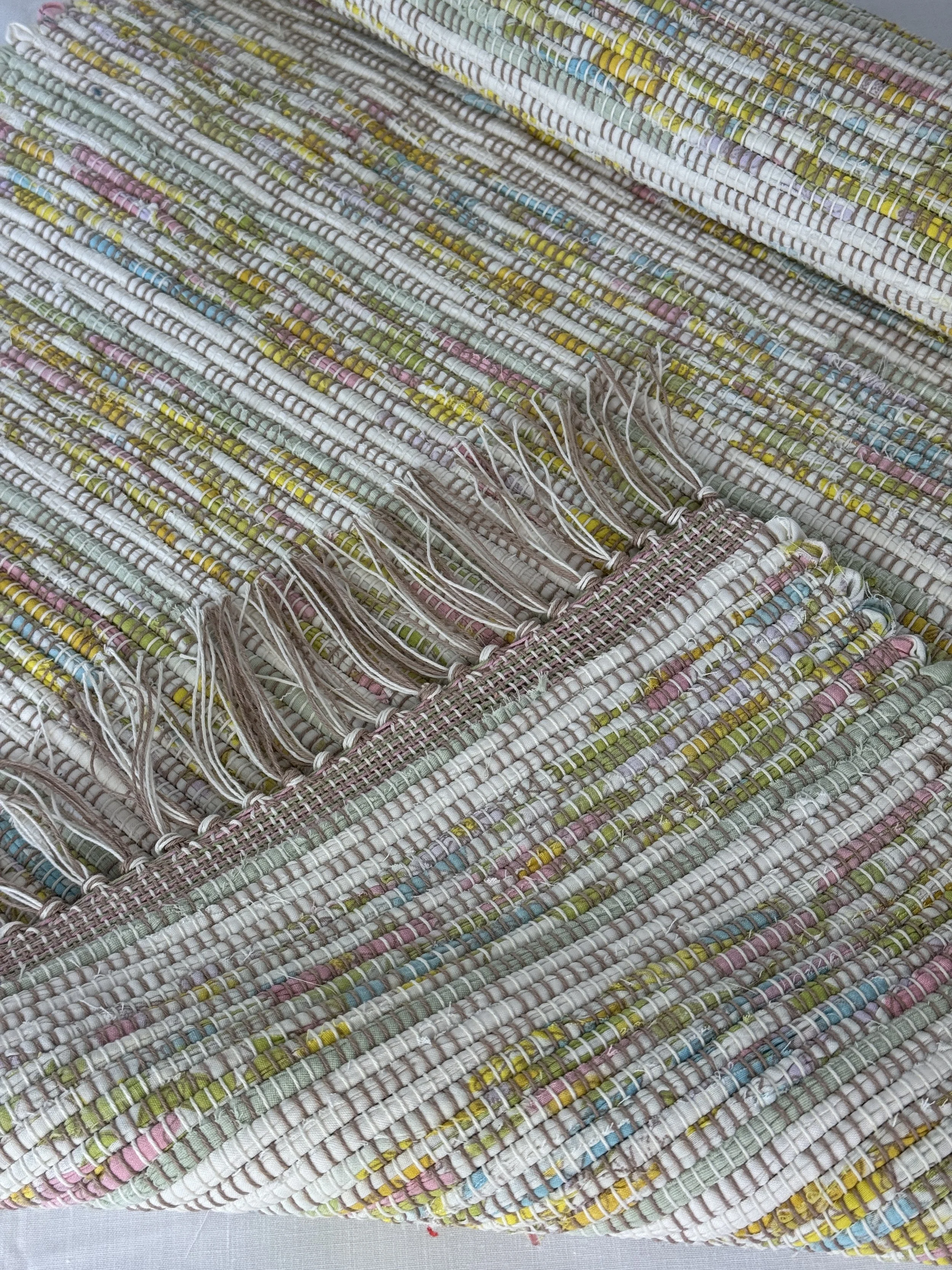 Folded handwoven rag rug showing reverse side and fringe