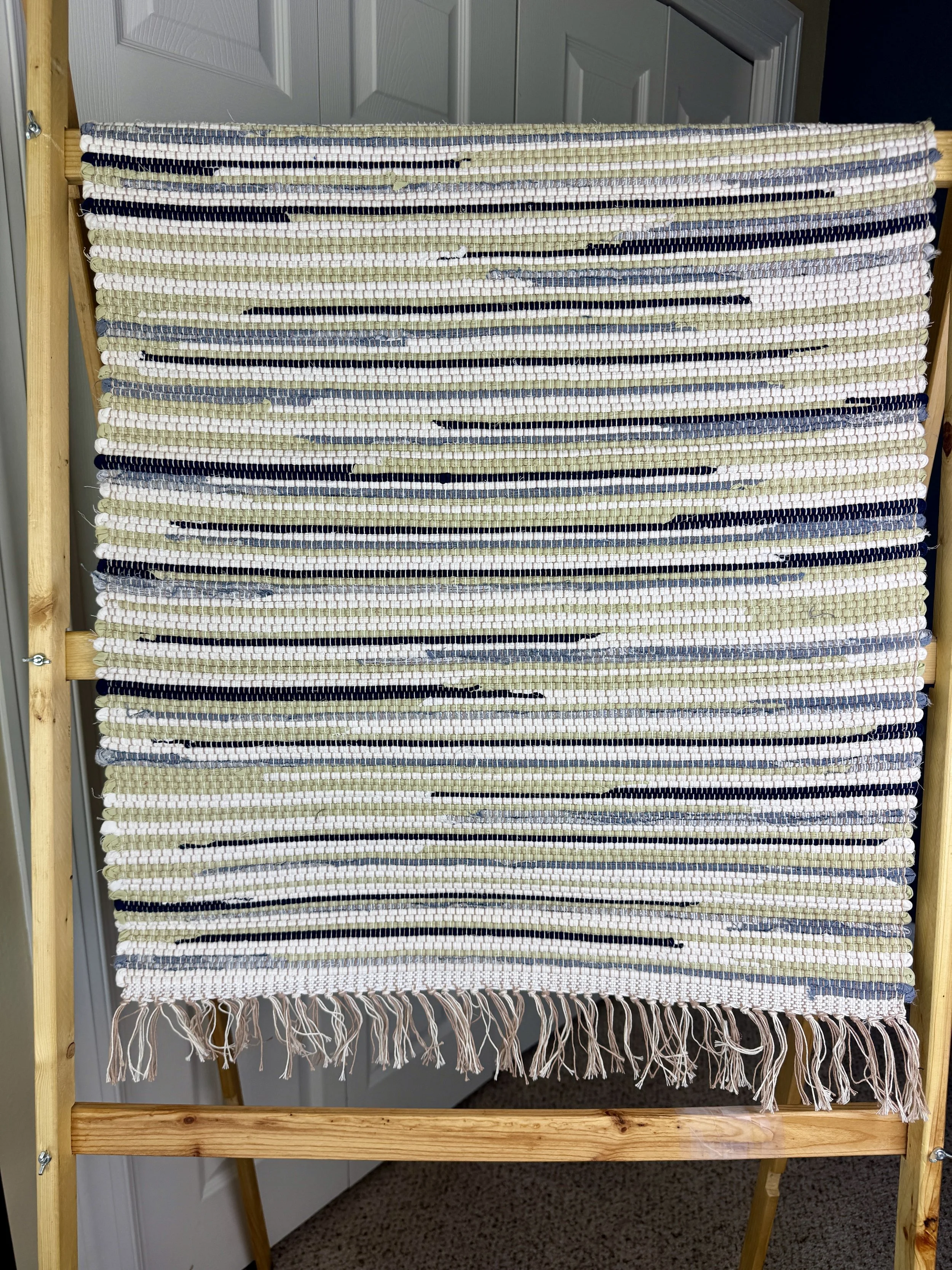 Hanging handmade recycled cotton blends rag rug showing pattern and fringe