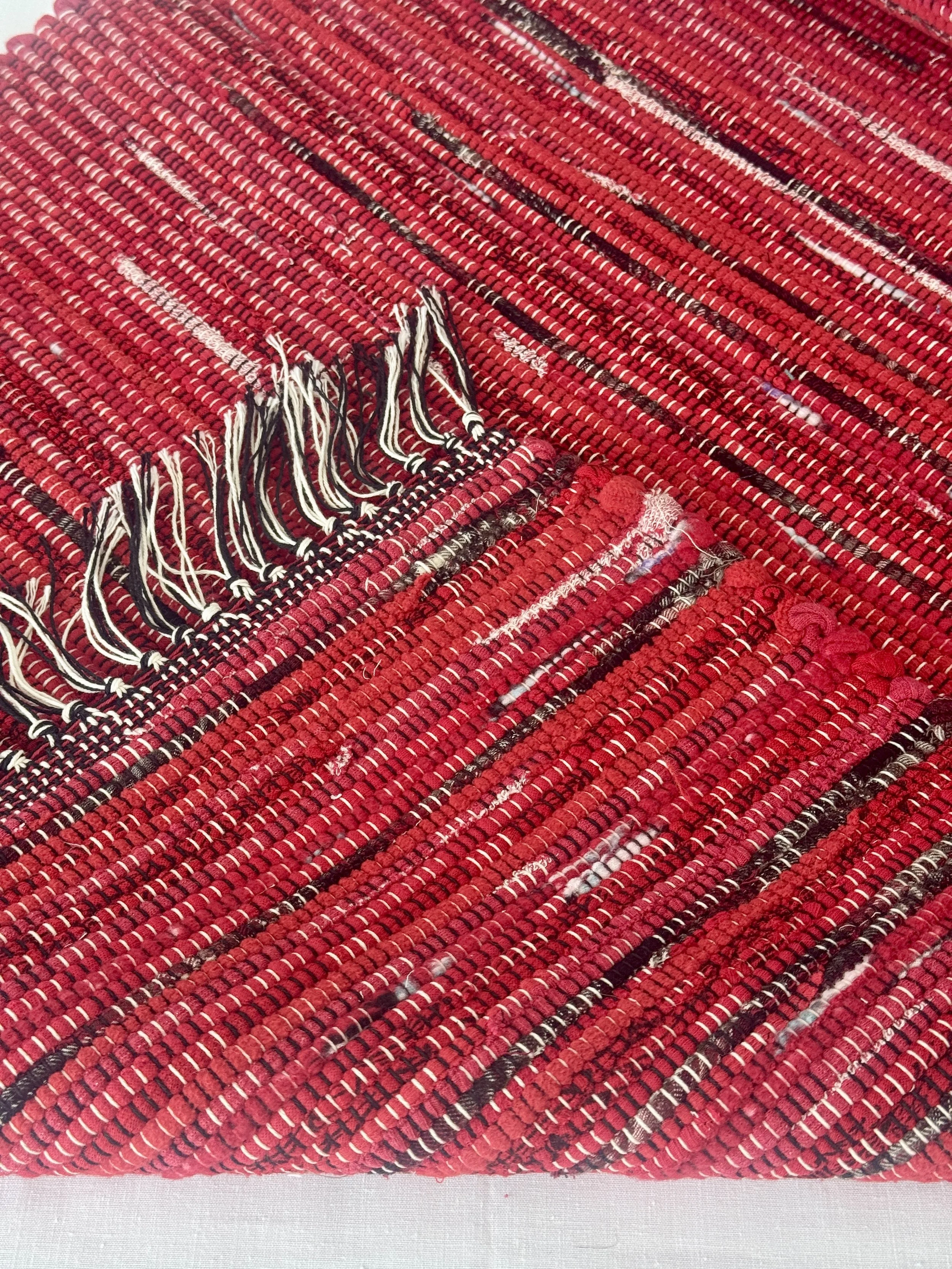 Folded handwoven recycled cotton textiles rag rug showing texture and fringe
