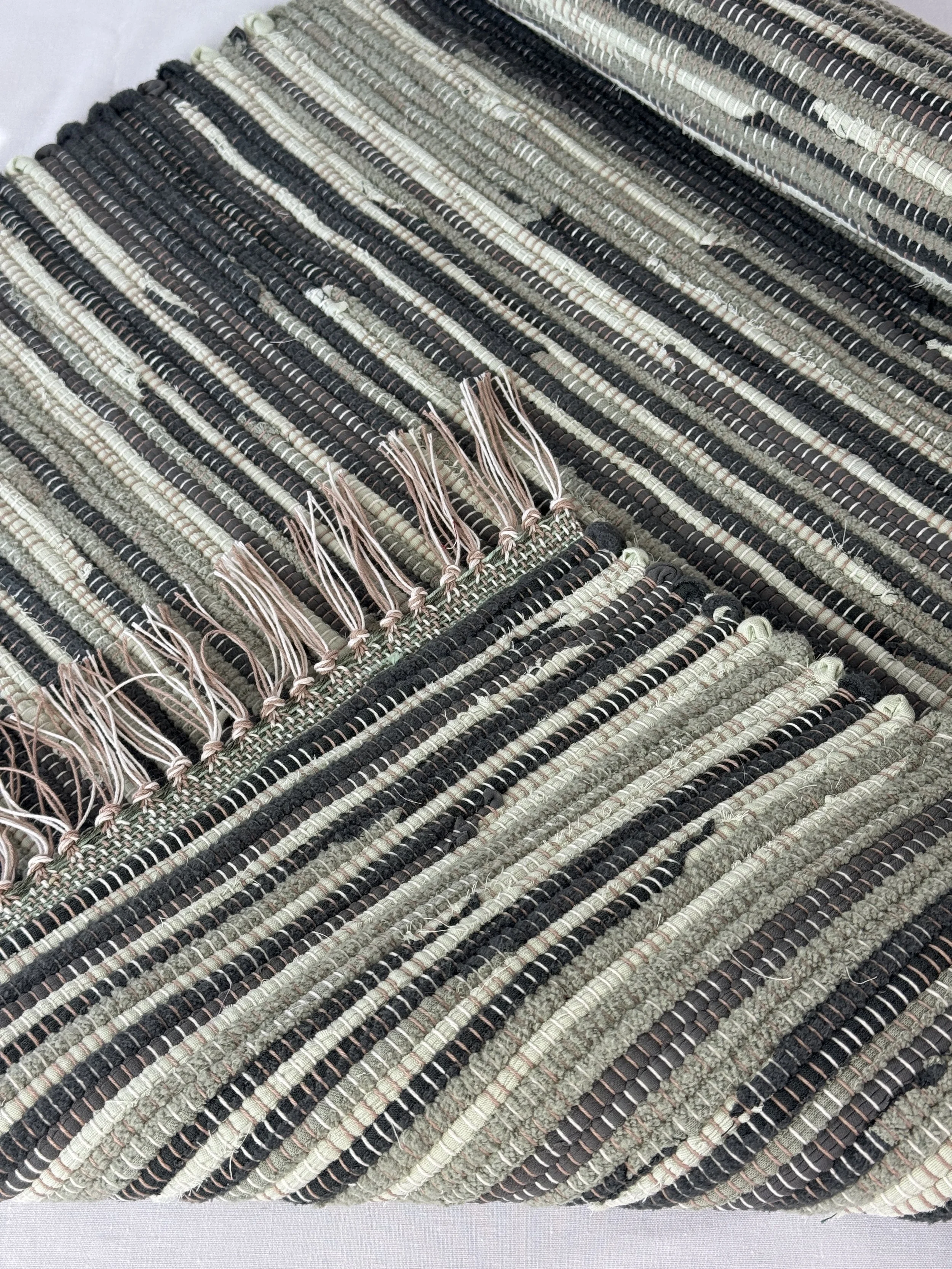 Folded handwoven rag rug showing reverse side and fringe