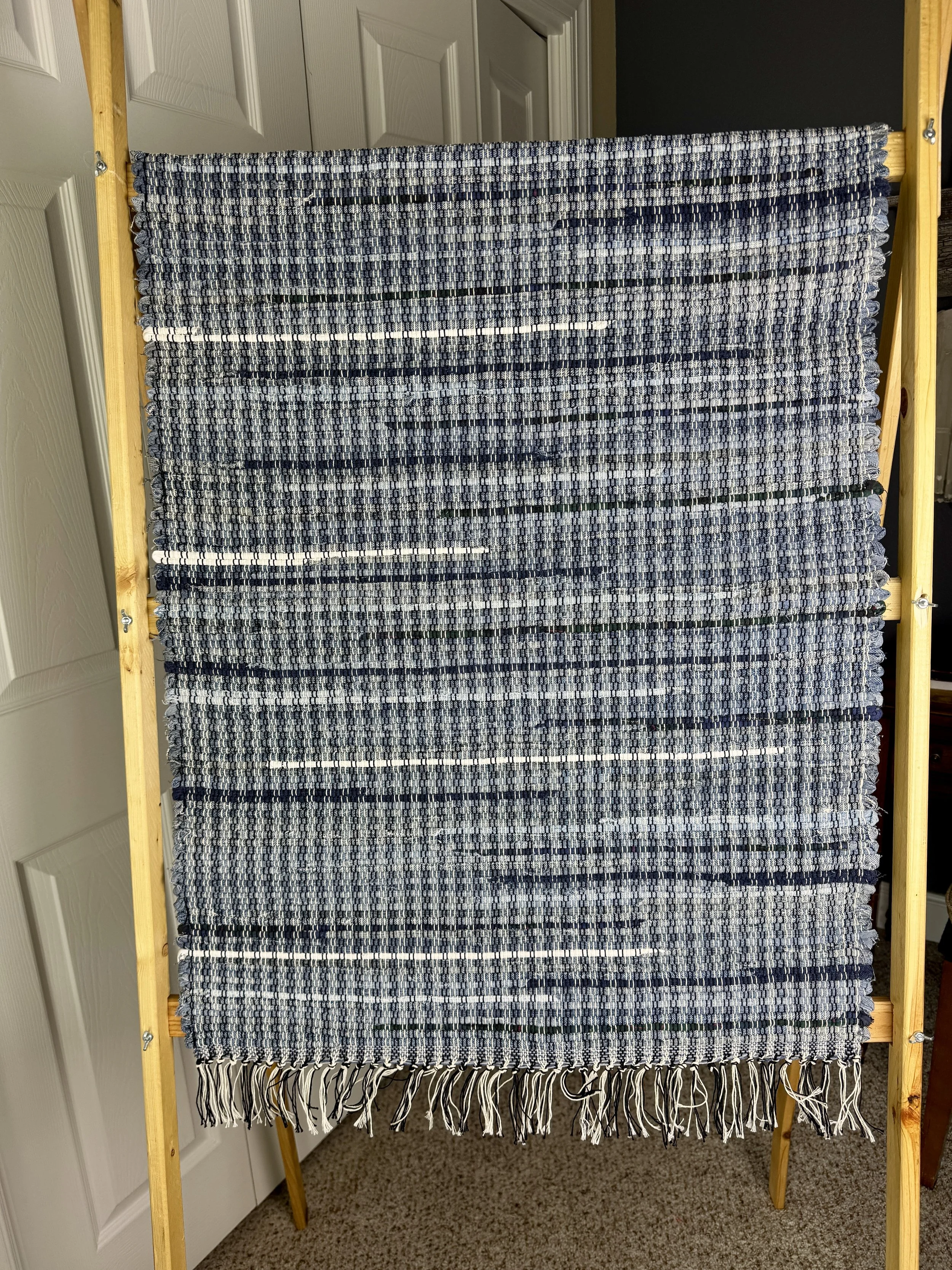 Hanging handmade upcycled denim  rag rug showing pattern and fringe