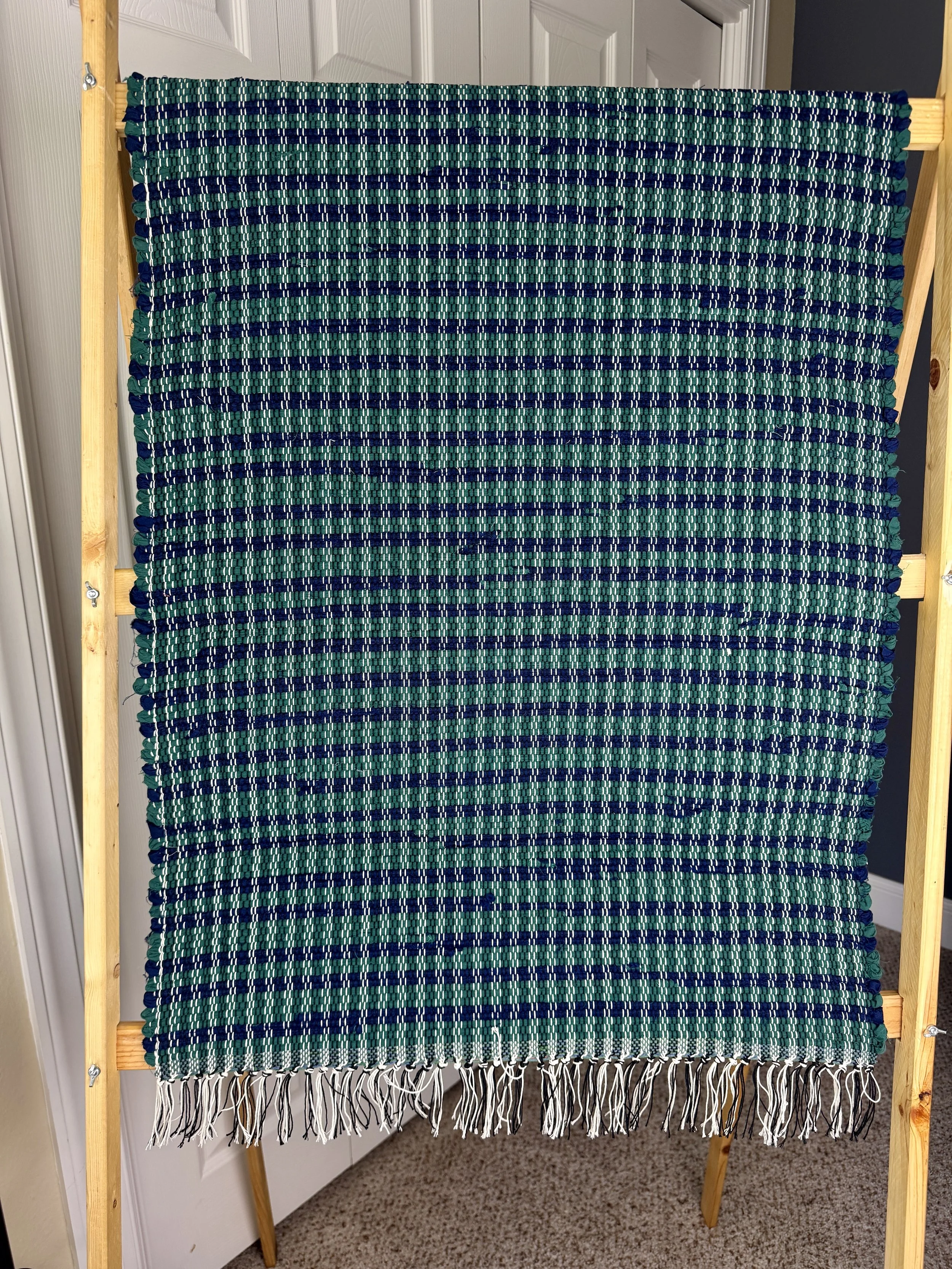 Hanging handmade recycled cotton blends rag rug showing pattern and fringe