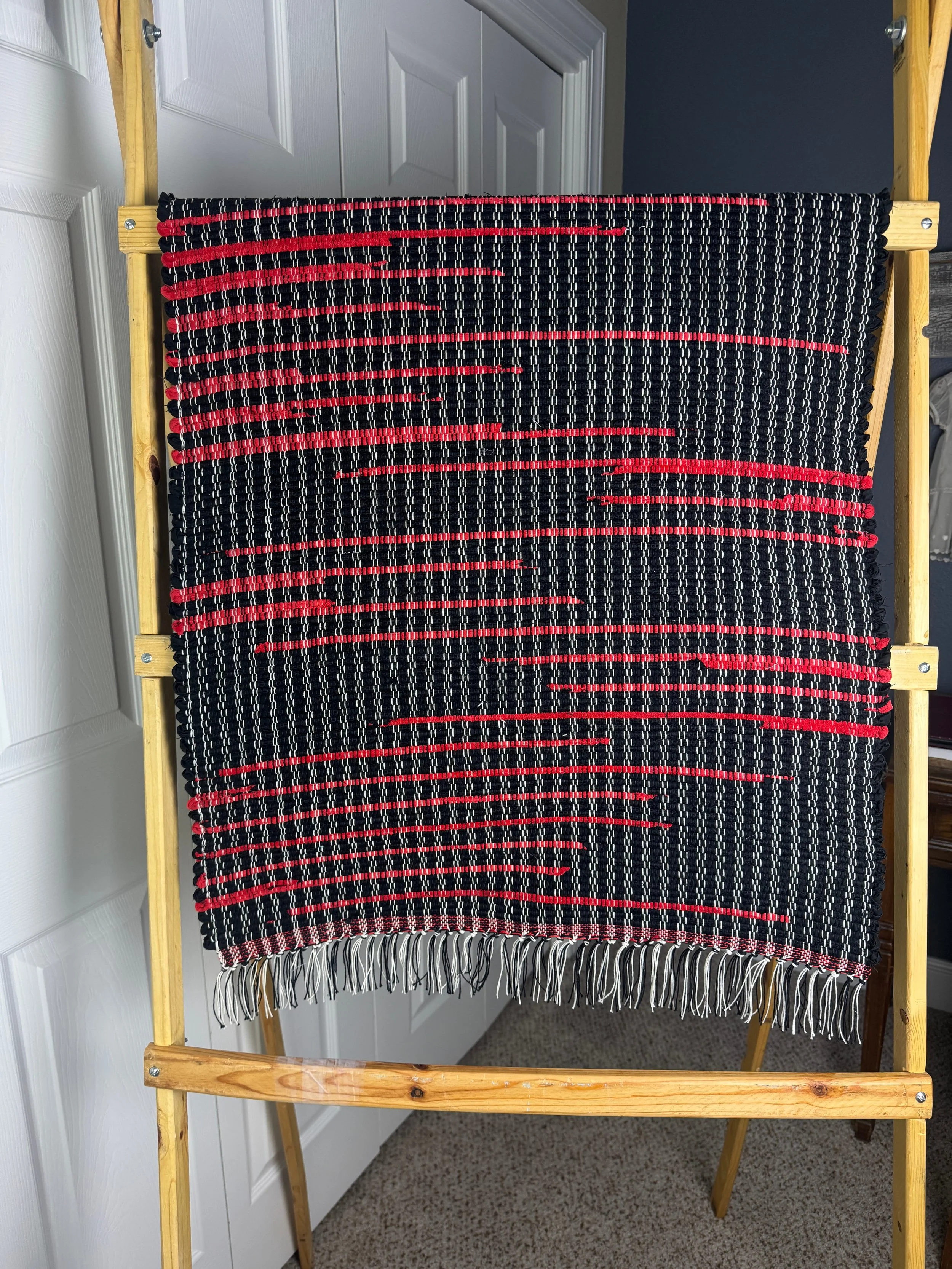 Handmade rag rug on loom hanging showing pattern