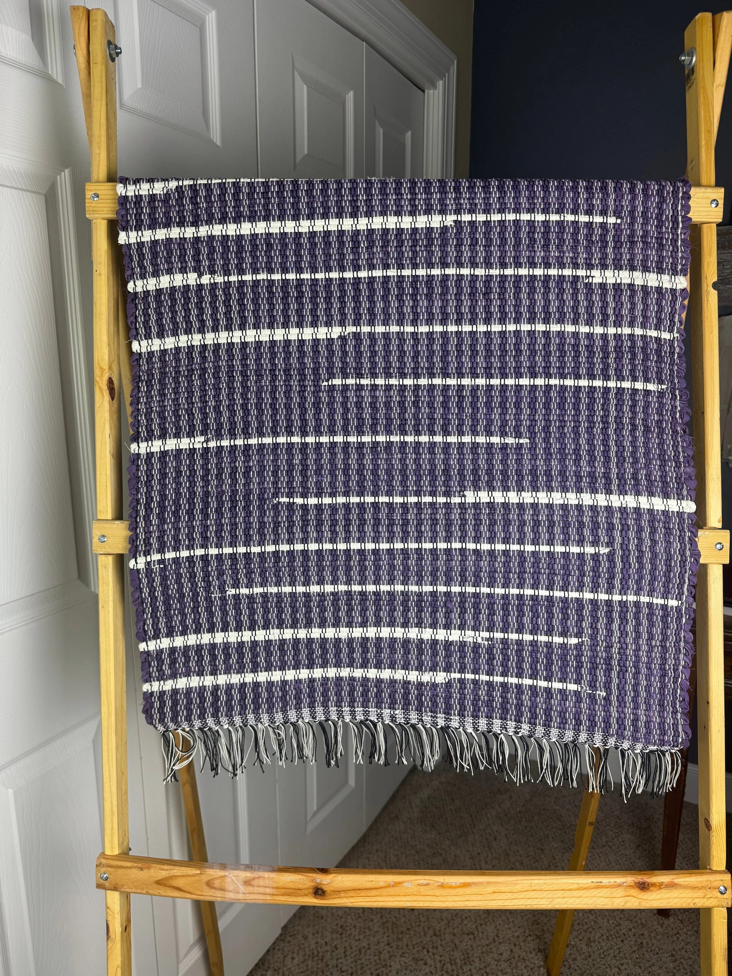 Handmade woven rag rug hanging to show pattern