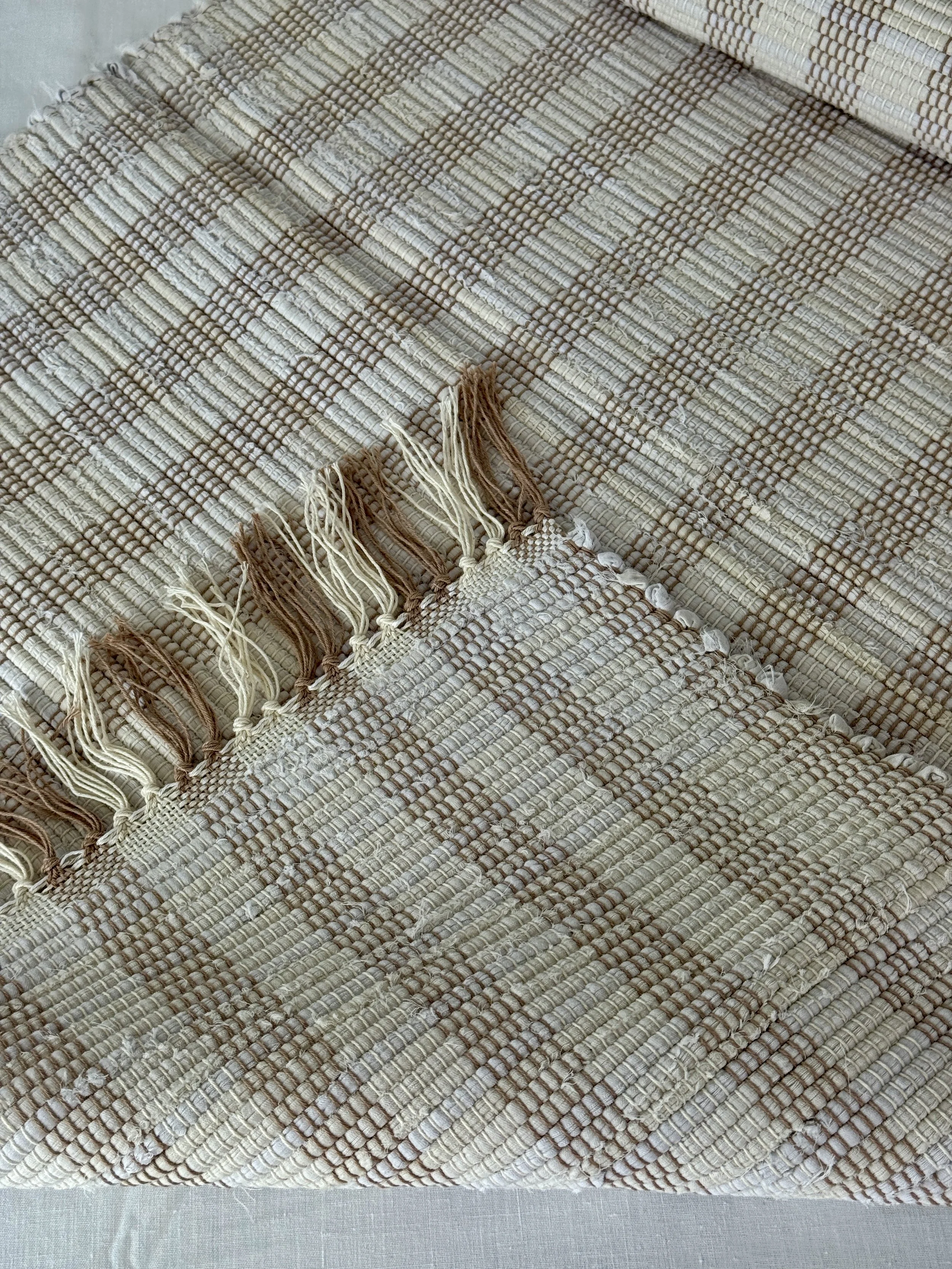 Folded handwoven rag rug showing reverse side and fringe