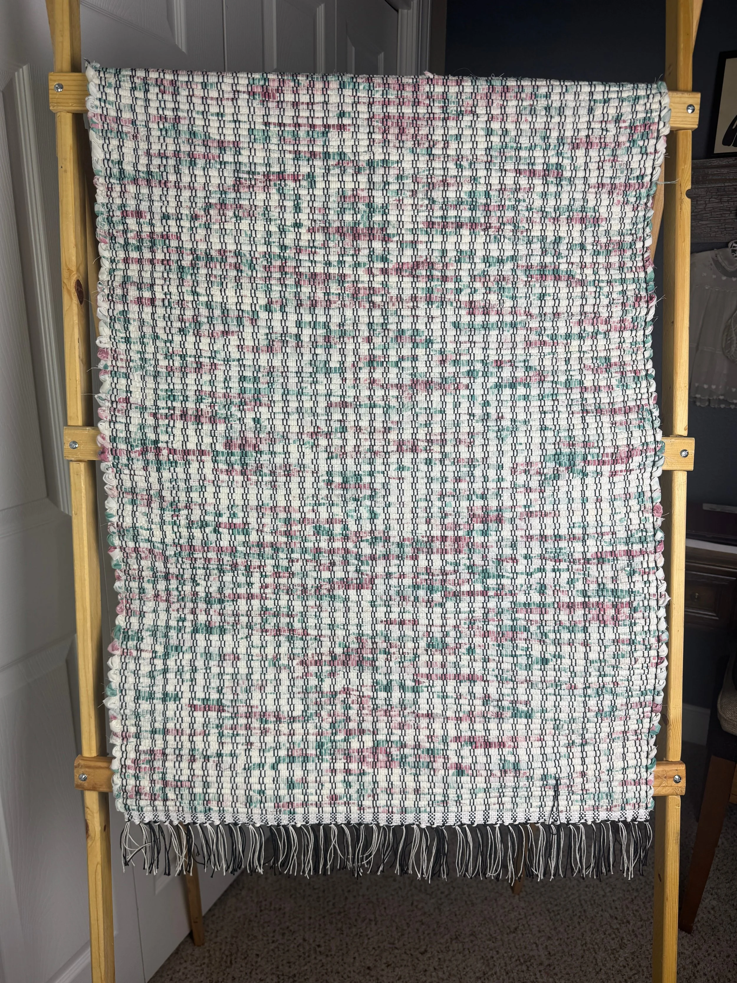 Pastel handwoven rag rug hanging to show pattern and fringe