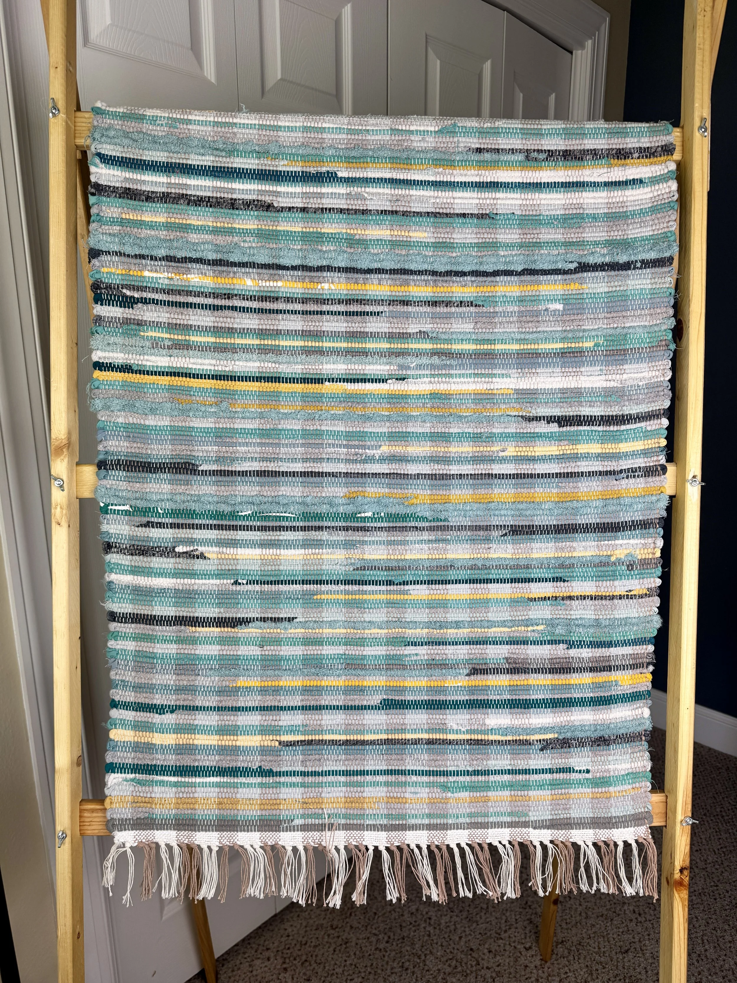 Hanging handmade recycled cotton blends rag rug showing pattern and fringe