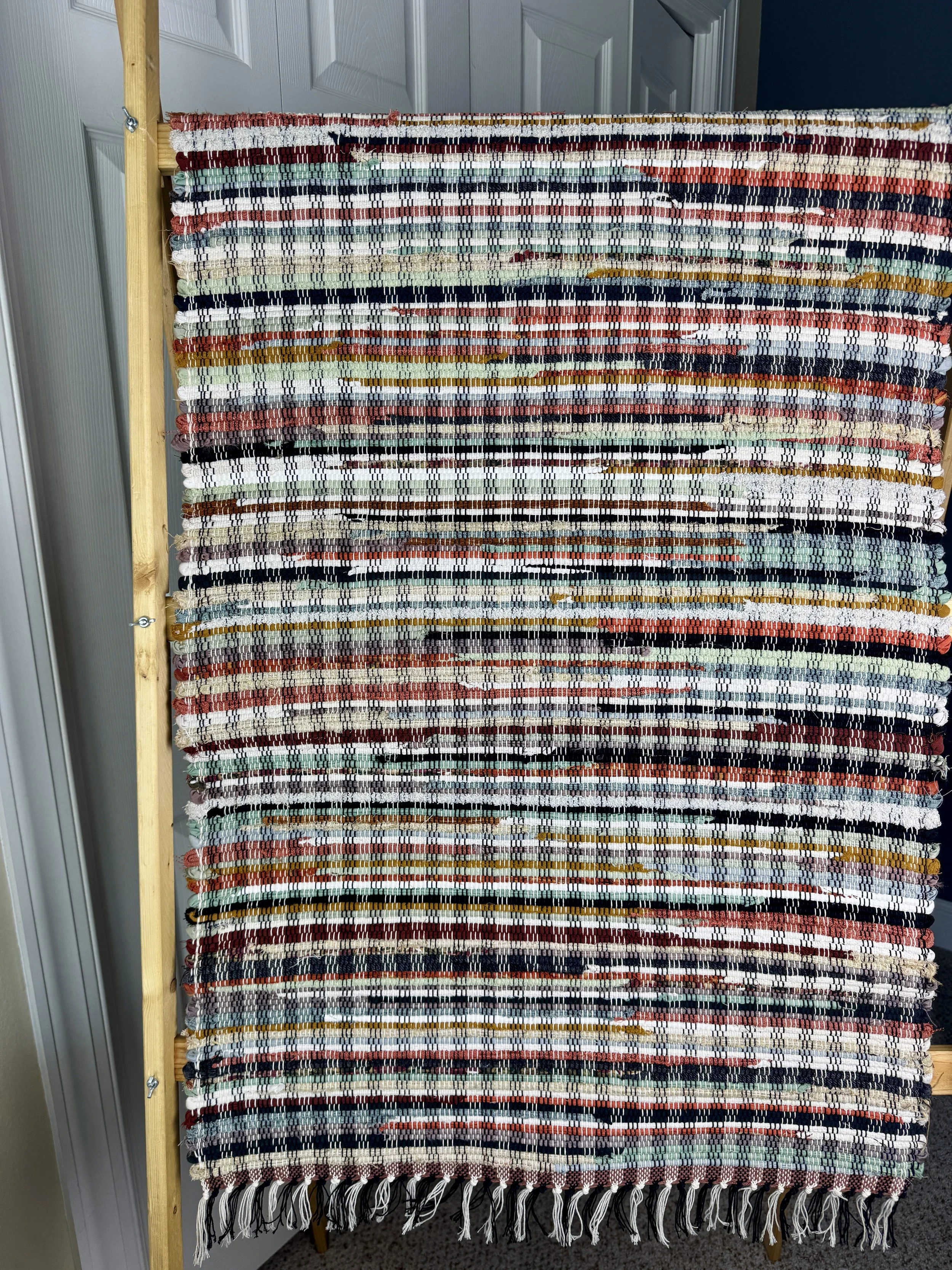 Hanging handmade recycled cotton  rag rug showing pattern and fringe