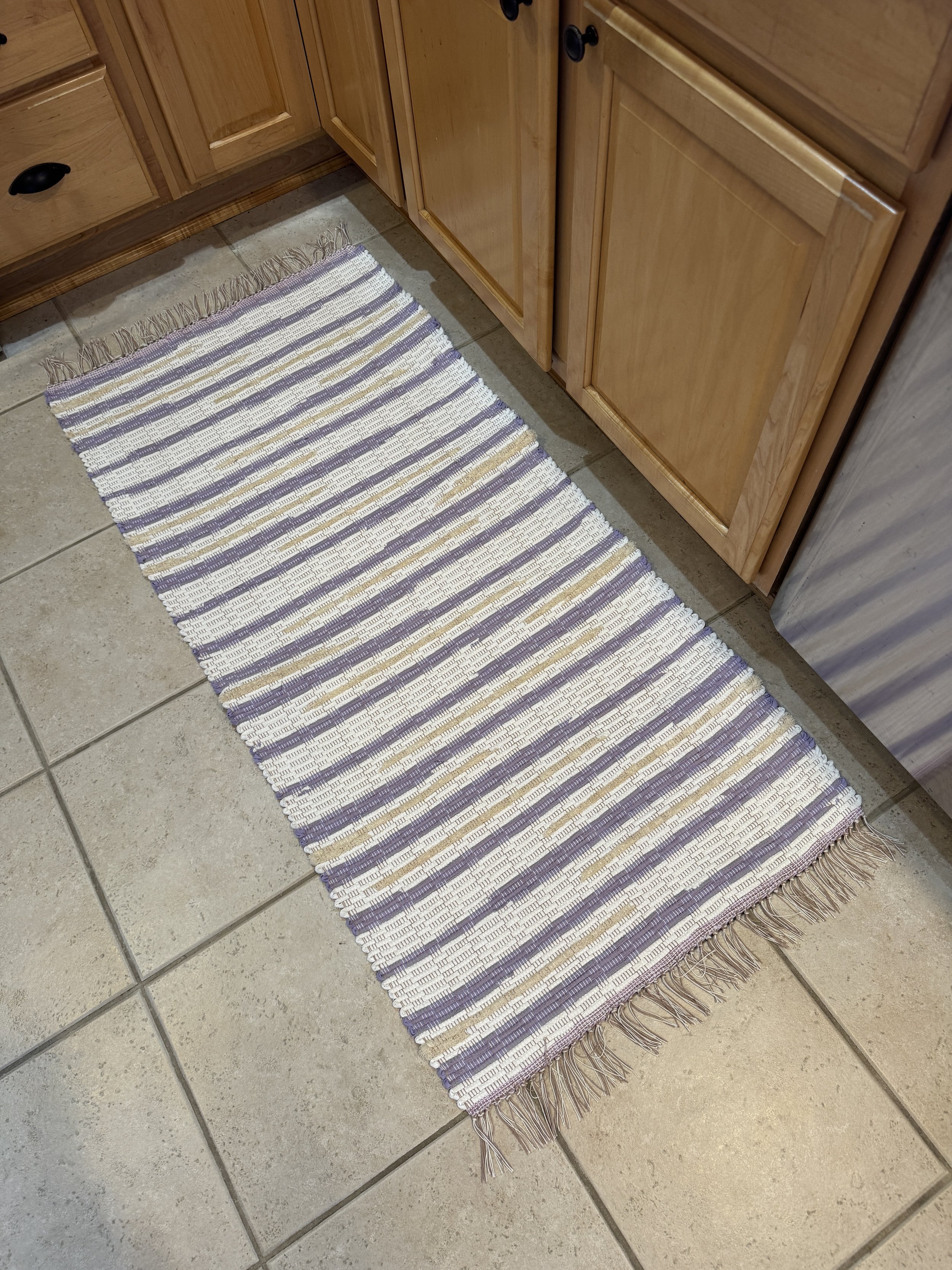 Handwoven lavender, white, tan rag rug displayed in kitchen showing pattern