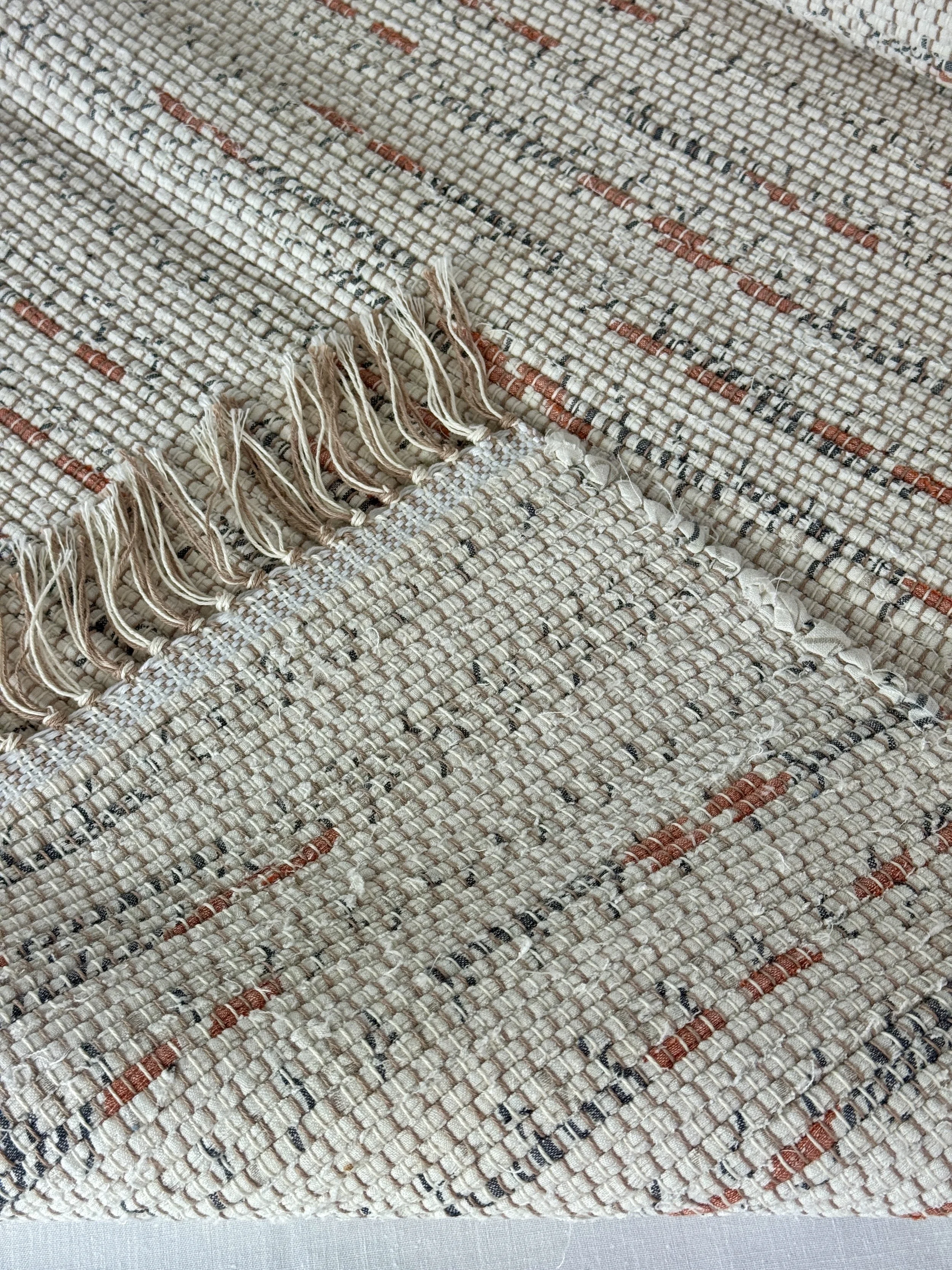 Folded handmade rug showing reverse side and fringe